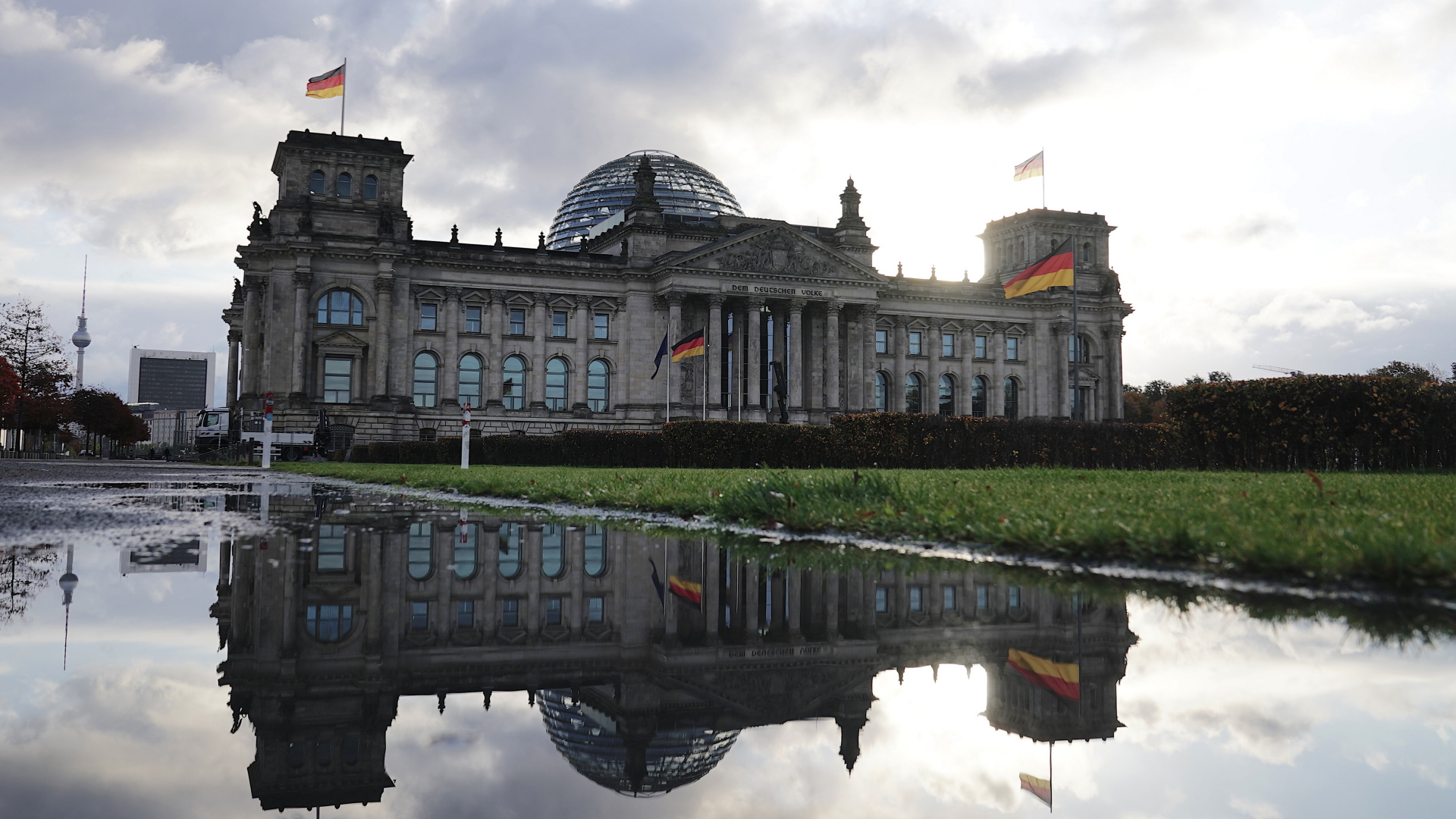 Das Reichstagsgebäude spiegelt sich in einer Pfütze