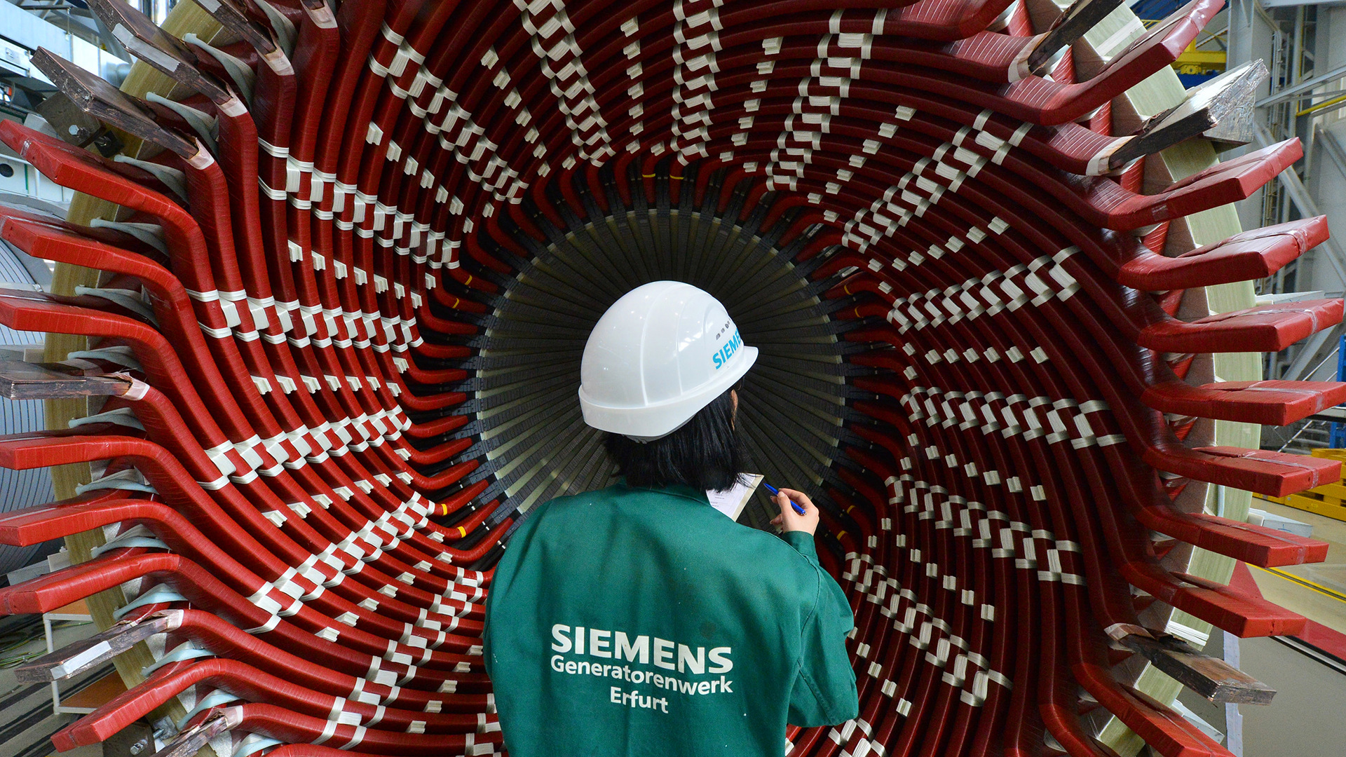 Eine Mitarbeiterin begutachtet einen Generatorständer im Siemens-Generatorenwerk.  | dpa
