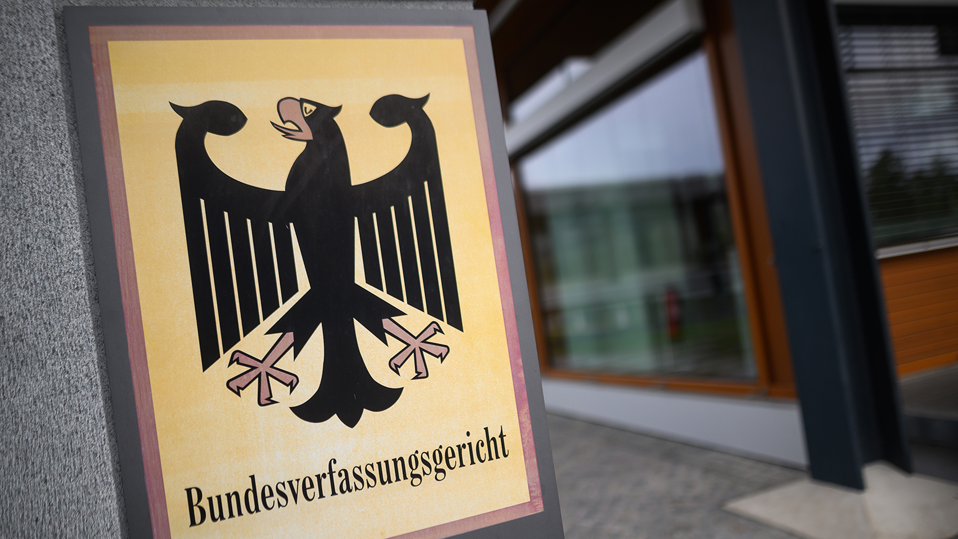 Ein Hinweisschild mit dem Bundesadler und dem Schriftzug "Bundesverfassungsgericht" steht vor dem Gericht in Karlsruhe. | dpa