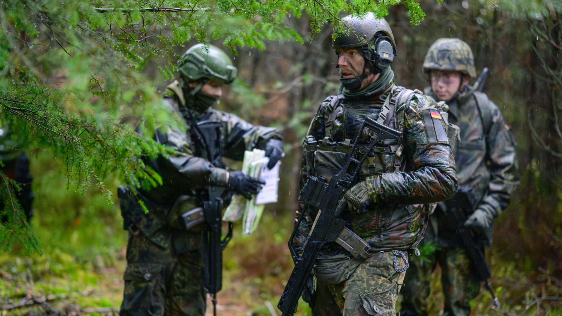 Soldaten der Bundeswehr stehen bei Regen während einer Übung im Wald.