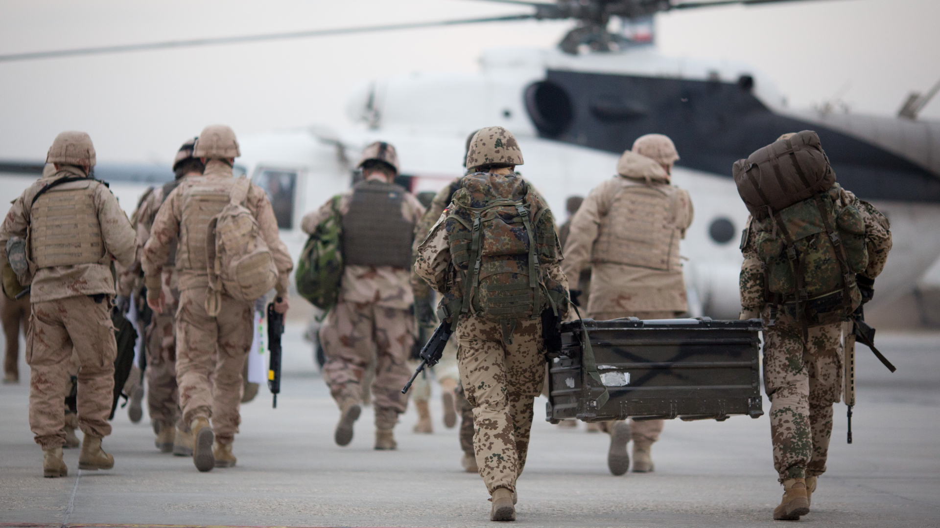Bundeswehrsoldaten tragen auf dem Flughafen in Masar-i-Scharif zu einem wartenden Hubschrauber eine Feldkiste (Archivbild vom 08.12.2015). | dpa