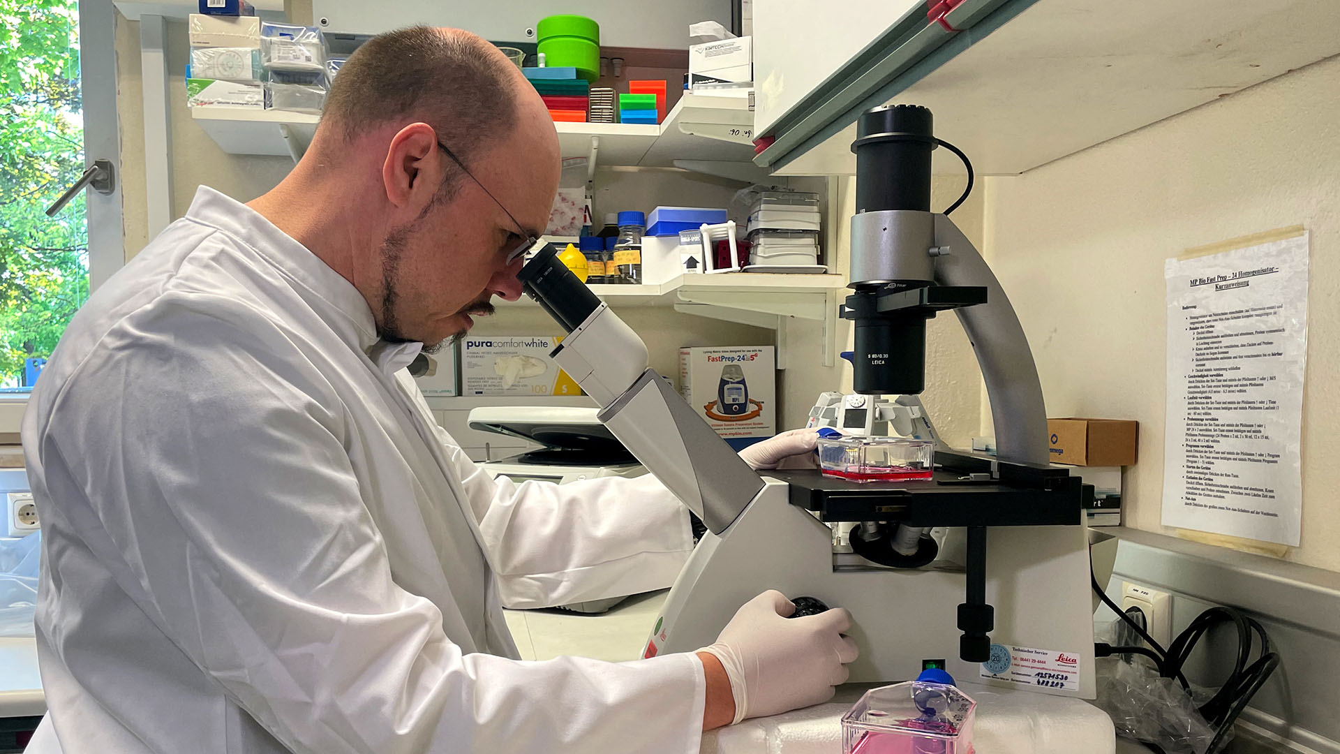 Roman Woelfel schaut in ein Mikroskop im  Labor des Instituts für Mikrobiologie der Bundeswehr in München.