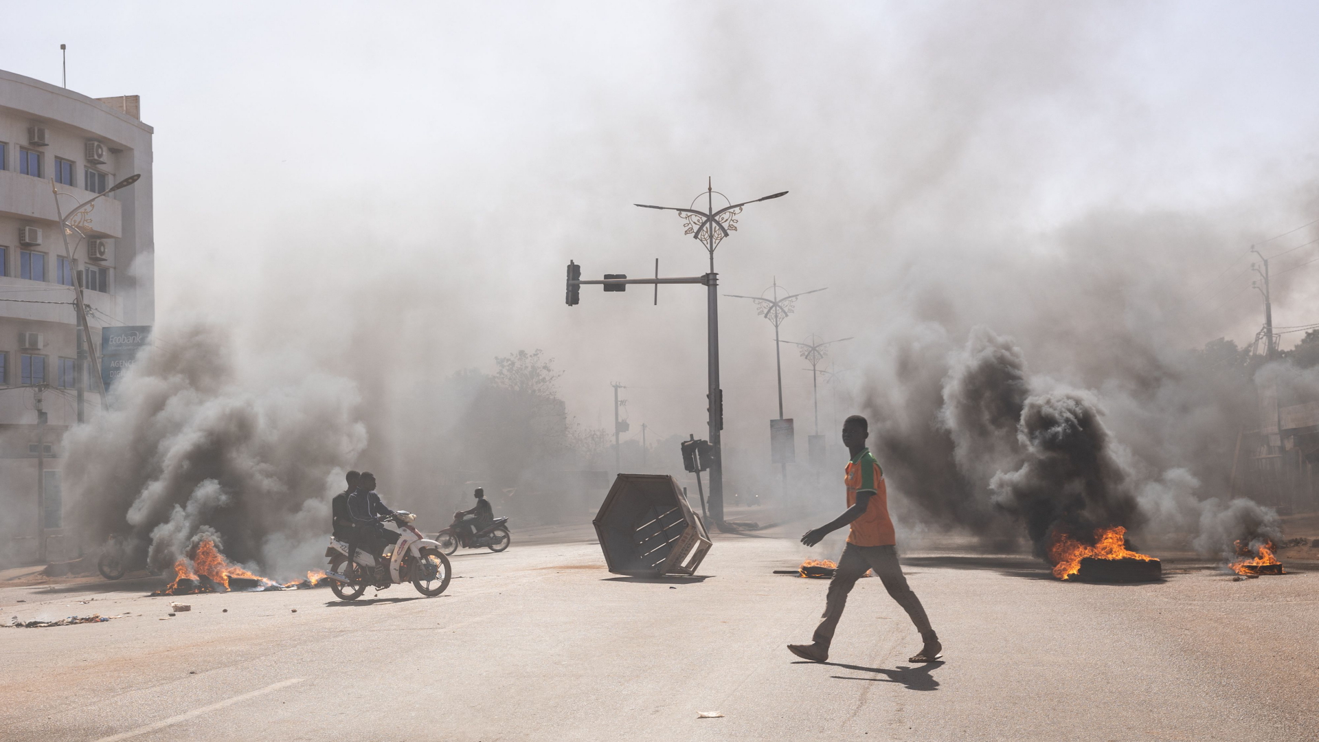 Ein Mann läuft an brennenden Barrikaden in Ouagadougou vorbei (Bild vom 23.01.2022). | AFP