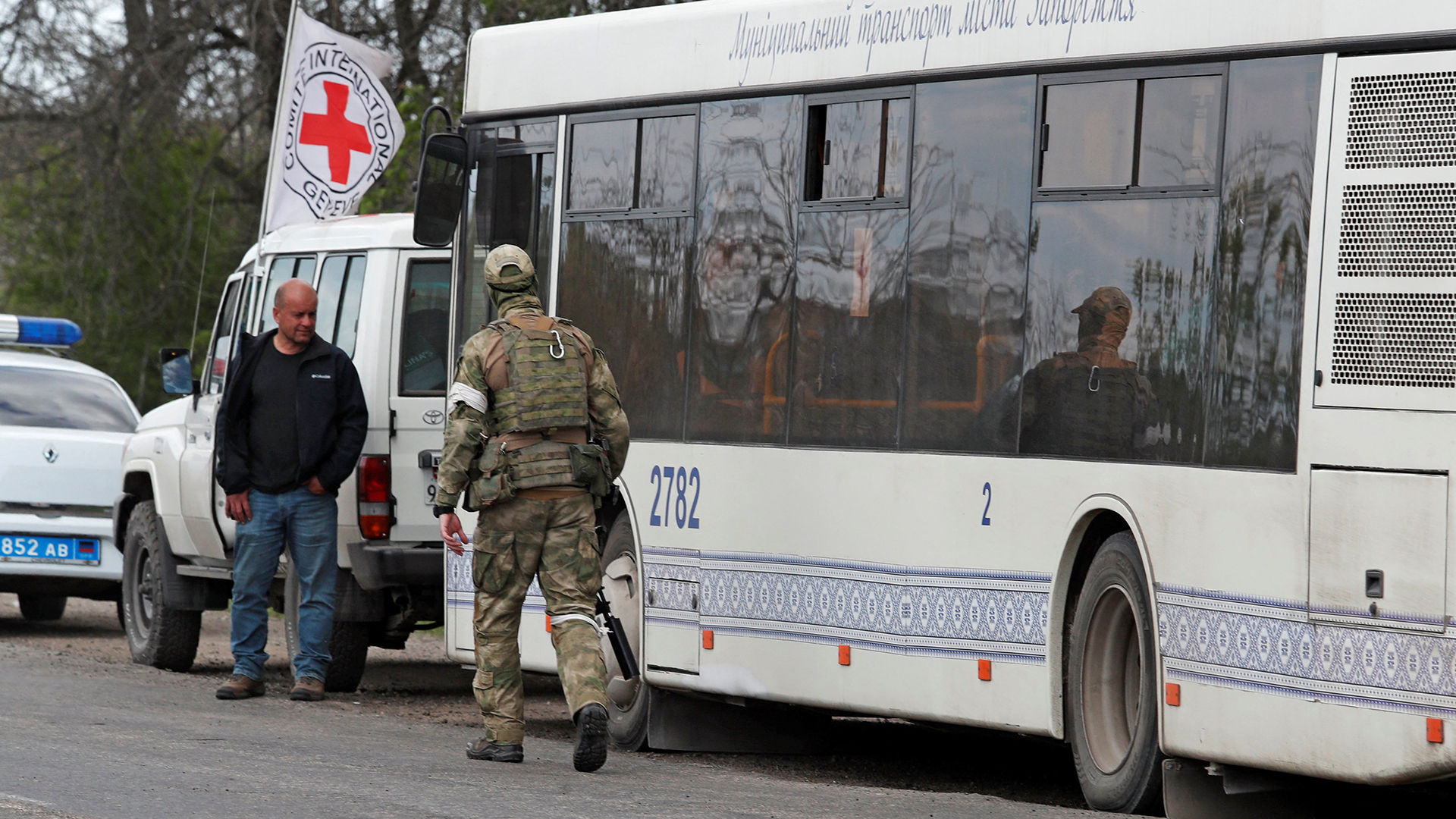 Ein Angehöriger der pro-russischen Truppen geht in der Region Donezk neben einem Bus mit Evakuierten aus dem Stahlwerk Azovstal in Mariupol. | REUTERS