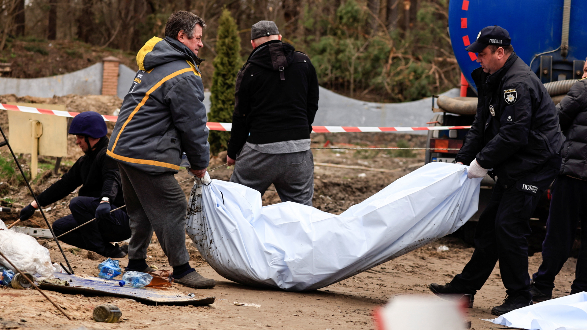 Polizisten tragen den Leichnam eines getöteten Zivilisten an einer Tankstelle in Busowa. | REUTERS
