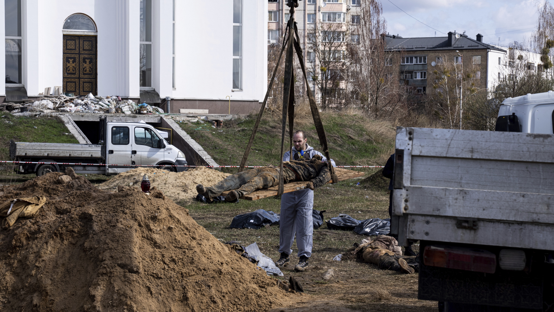Ein Gerichtsmediziner birgt die Leiche eines Anwohners aus einem Massengrab am Stadtrand von Butscha.