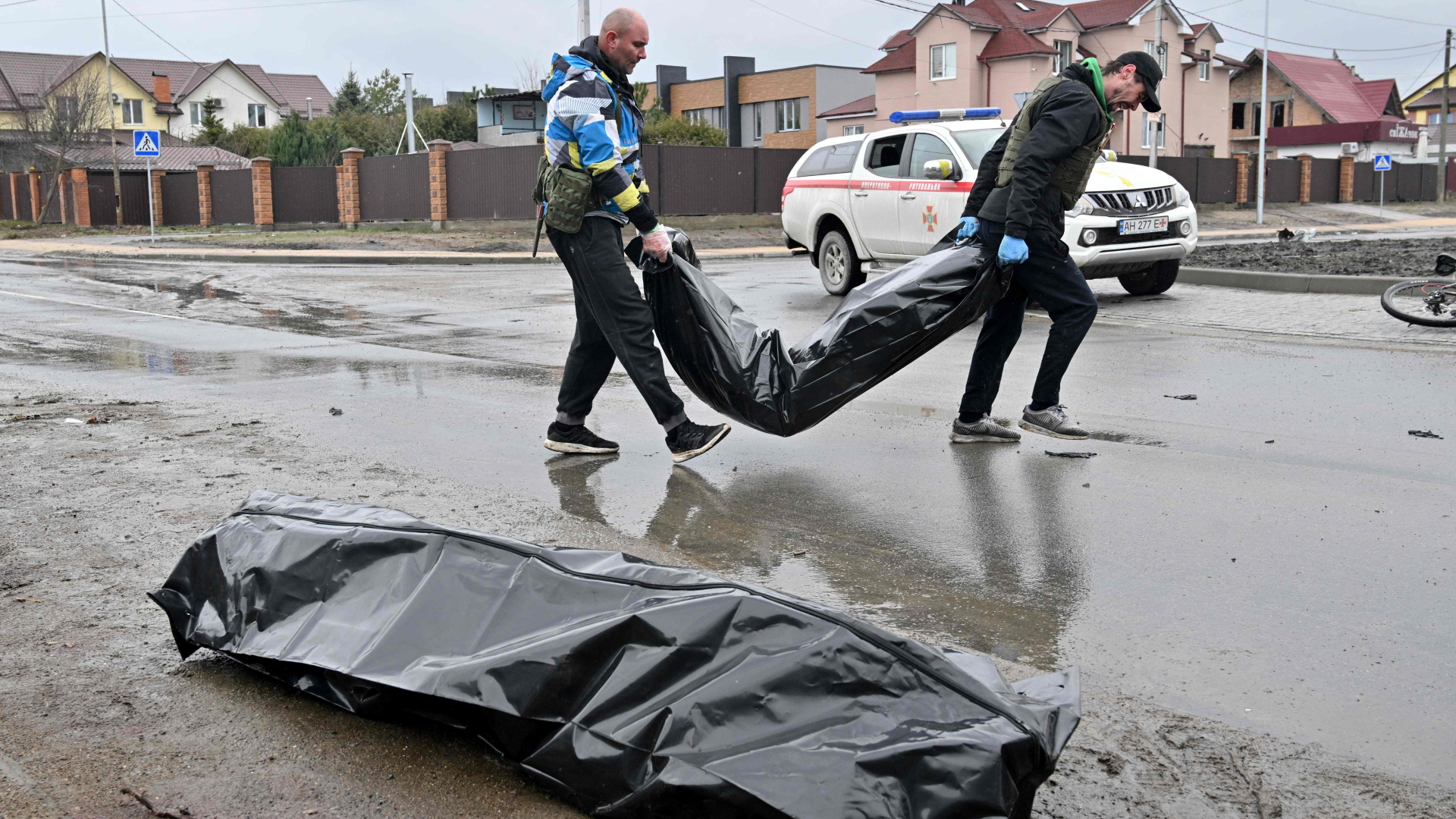 Zwei Männer tragen in der ukrainischen Stadt Butscha Leichensäcke weg | AFP
