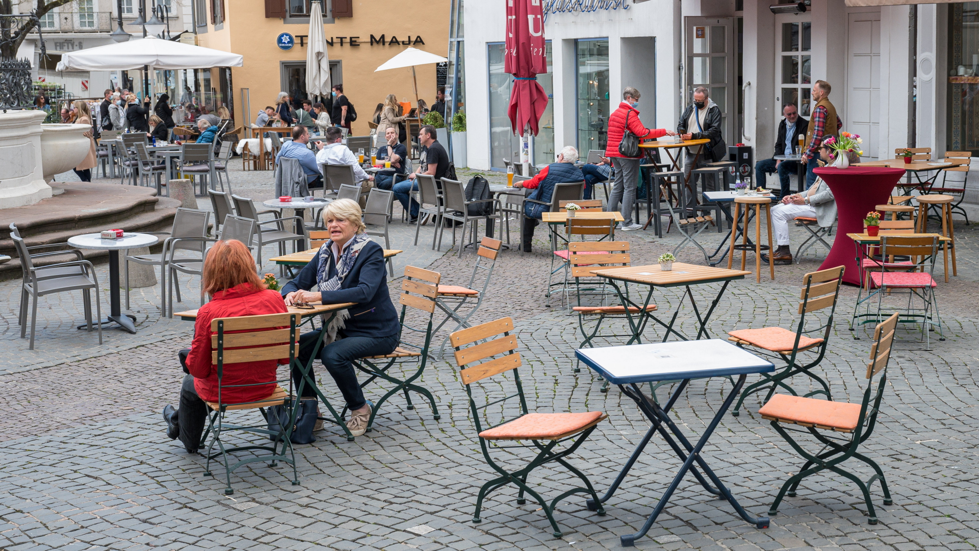 Einige wenige Menschen sitzen vor einem Café in Saarbrücken