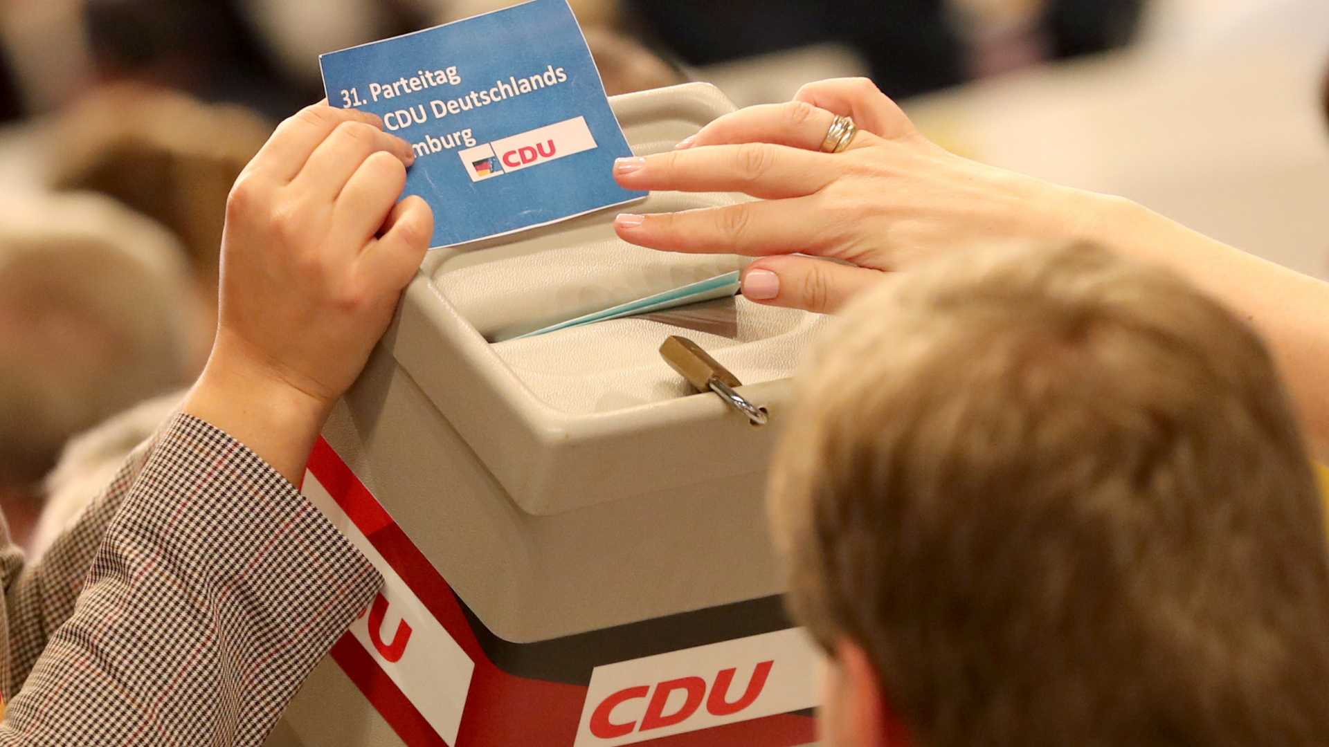 Eine Frau hält über einer Wahlurne den Flyer des CDU-Bundesparteitages. | dpa