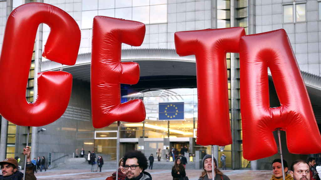 Demonstranten halten CETA-Schriftzug in Brüssel in die Höhe