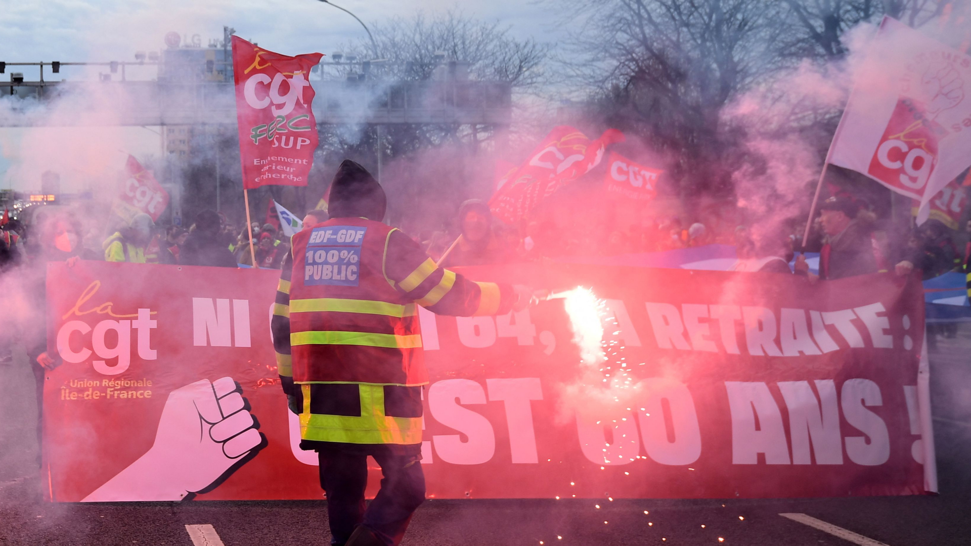 Gewerkschafter der CGT blockieren mit Banner und Bengalos eine Straße in Paris. | AFP