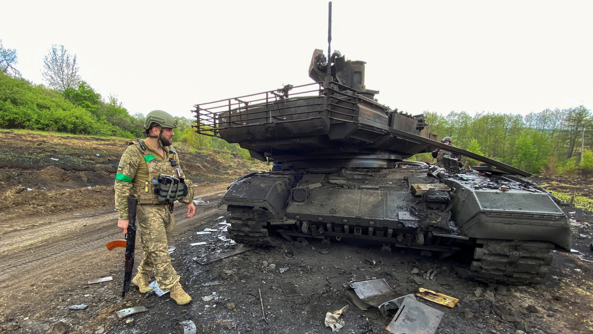 Ein ukrainischer Soldat steht vor einem zerstörtem russischem Panzer in Charkiw. | REUTERS