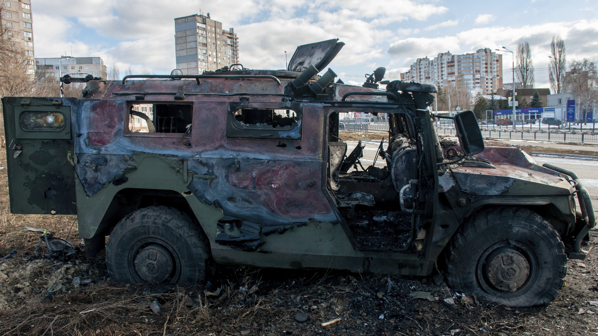 Ein ausgebranntes Militärfahrzeug steht vor Wohnhäusern. | dpa
