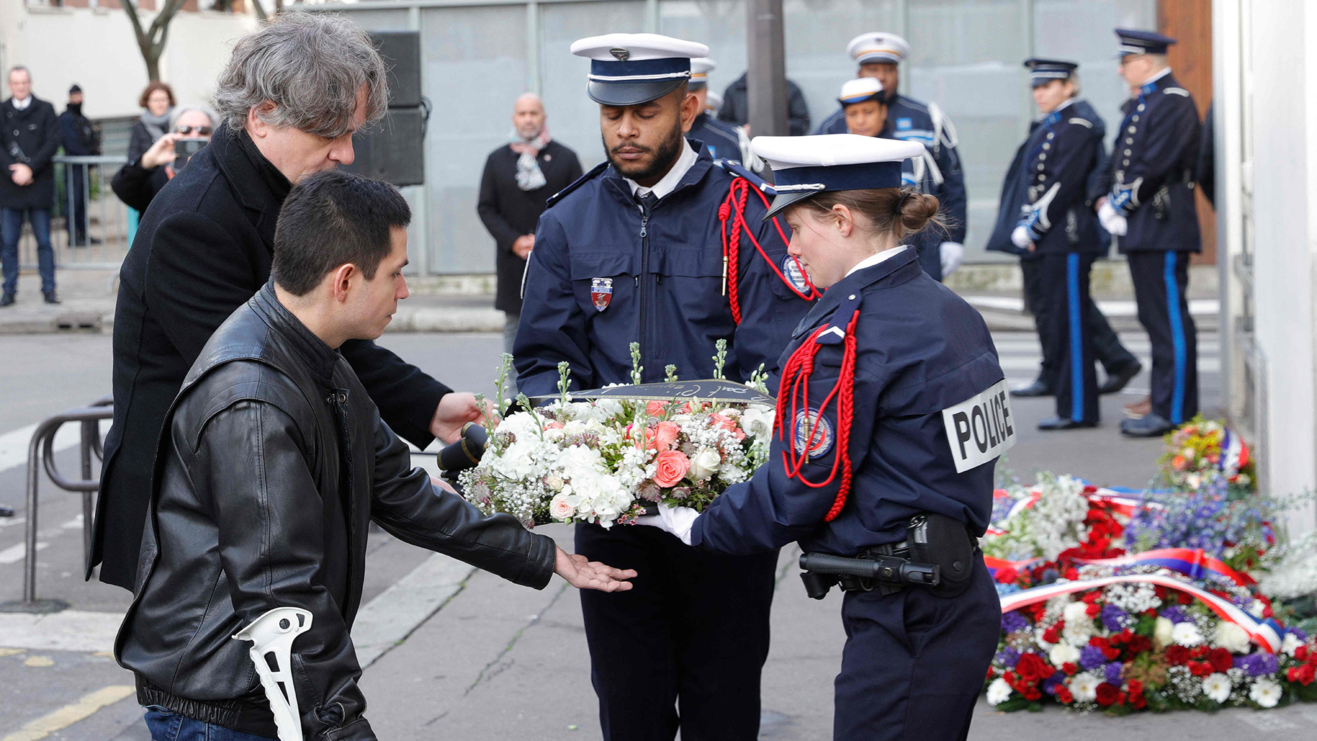 Simon Fieschi und Laurent Sourisseau (Riss) übergeben Polizeikräften einen Kranz bei der Gedenkveranstaltung zum Attentat auf das Satiremagazin Charlie Hebdo. | AFP