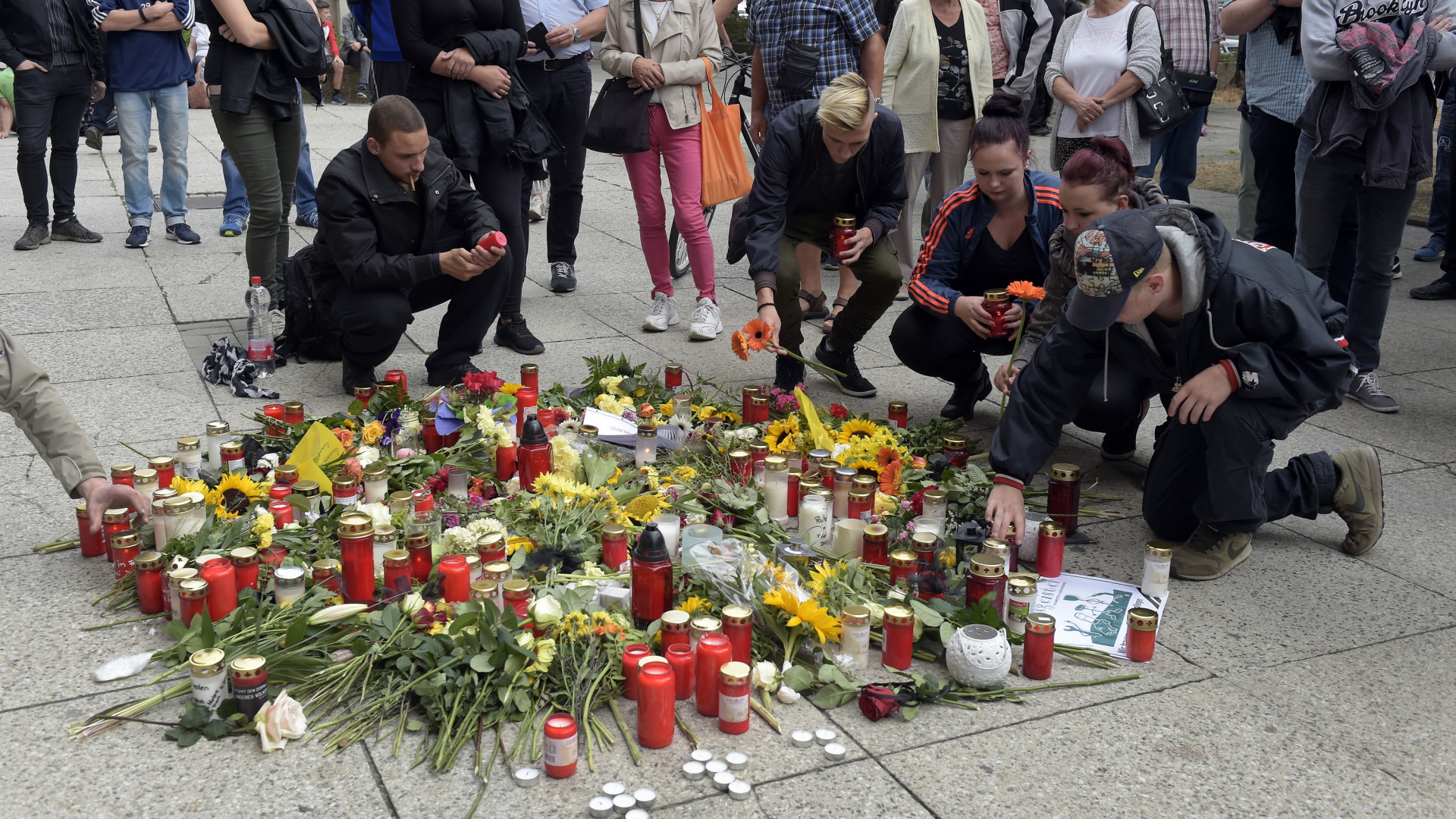 Menschen entzünden Kerzen und legen Blumen in Chemnitz nieder. | AP