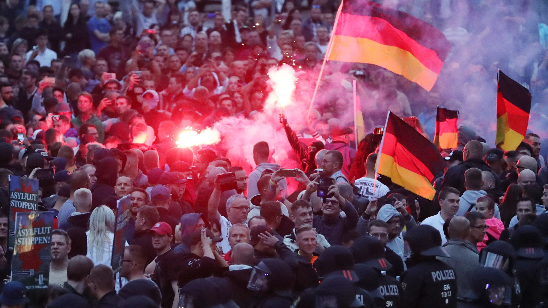 Demonstranten der rechten Szene zünden Pyrotechnik und schwenken Deutschlandfahnen.  | dpa