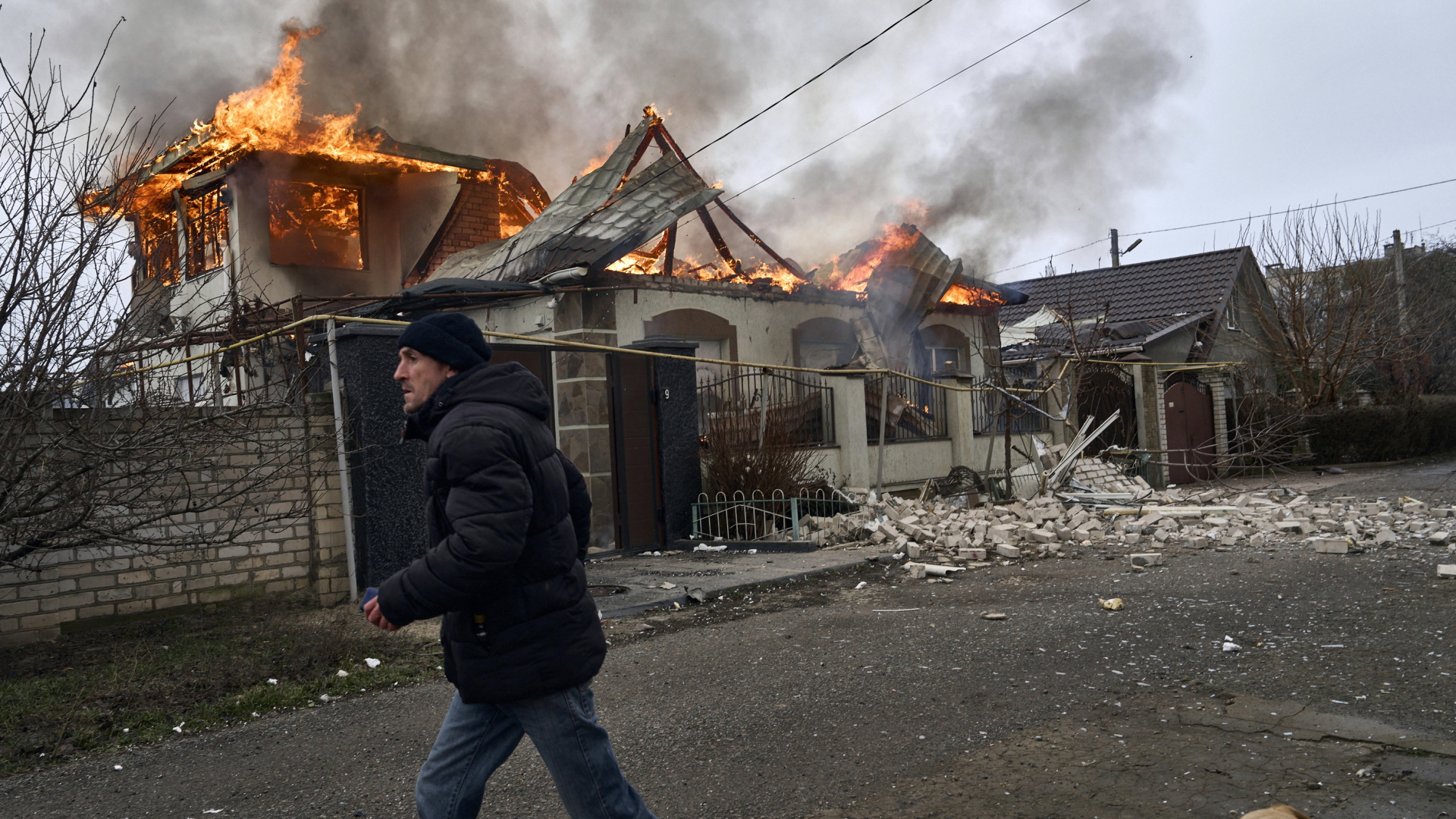 Ein Mann läuft an einem brennenden Haus in Cherson vorbei. | AP