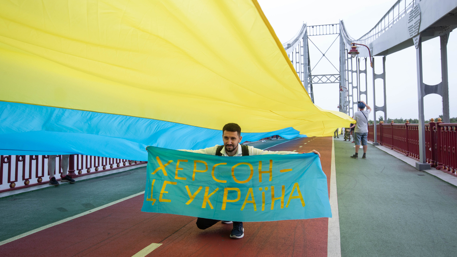 "Cherson gehört zur Ukraine" steht auf einem Banner, das ein Mann in Kiew in die Höhe hält. | picture alliance / ZUMAPRESS.com