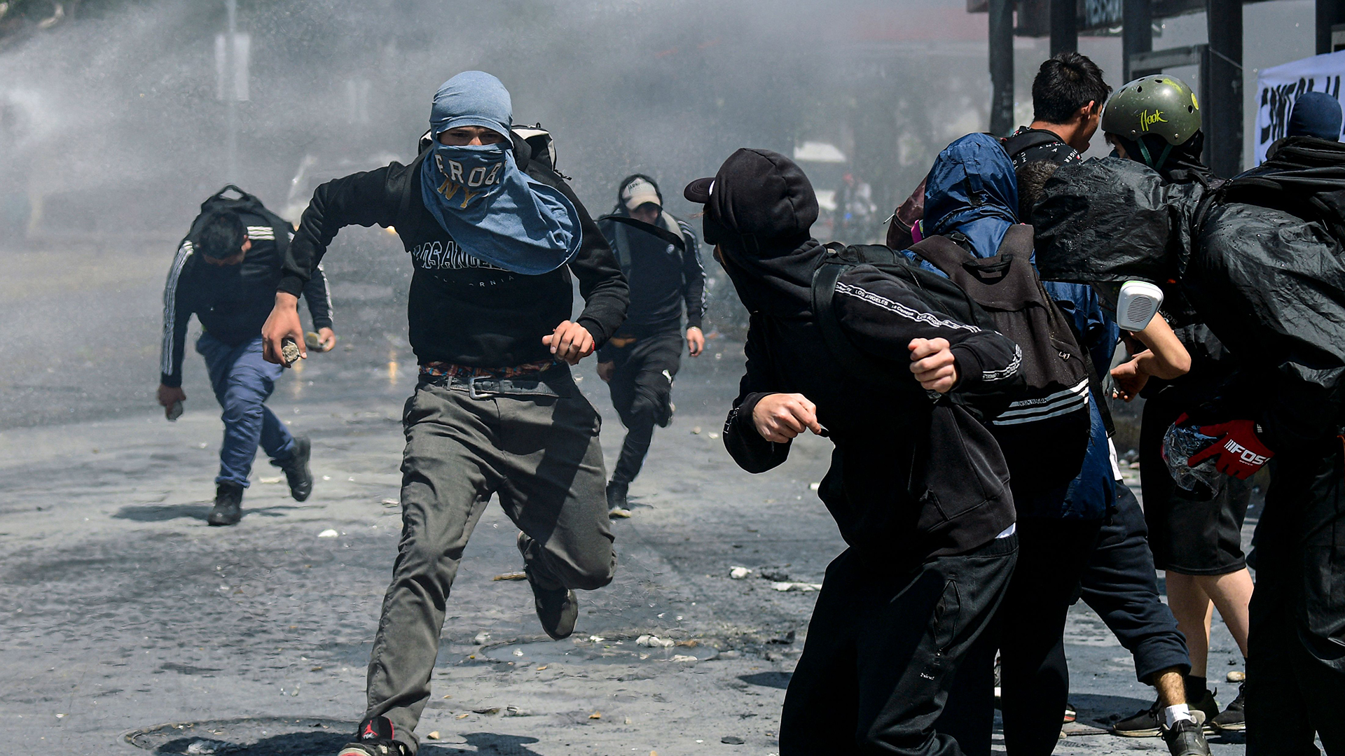 Demonstranten rennen während einer Demonstration in Santiago (Chile) eine Straße entlang. | AFP