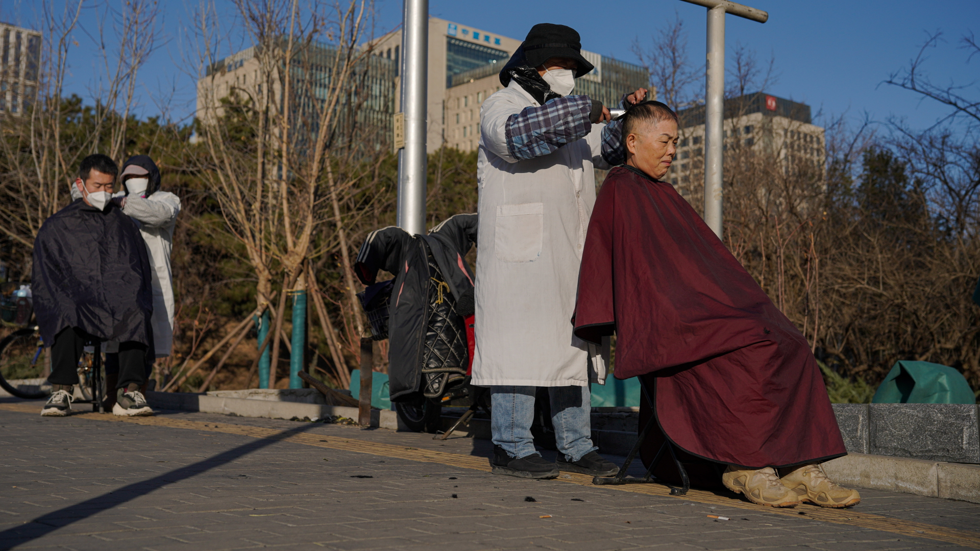 Eine Frau bekommt in Peking im Freien ihre Haare geschnitten | EPA