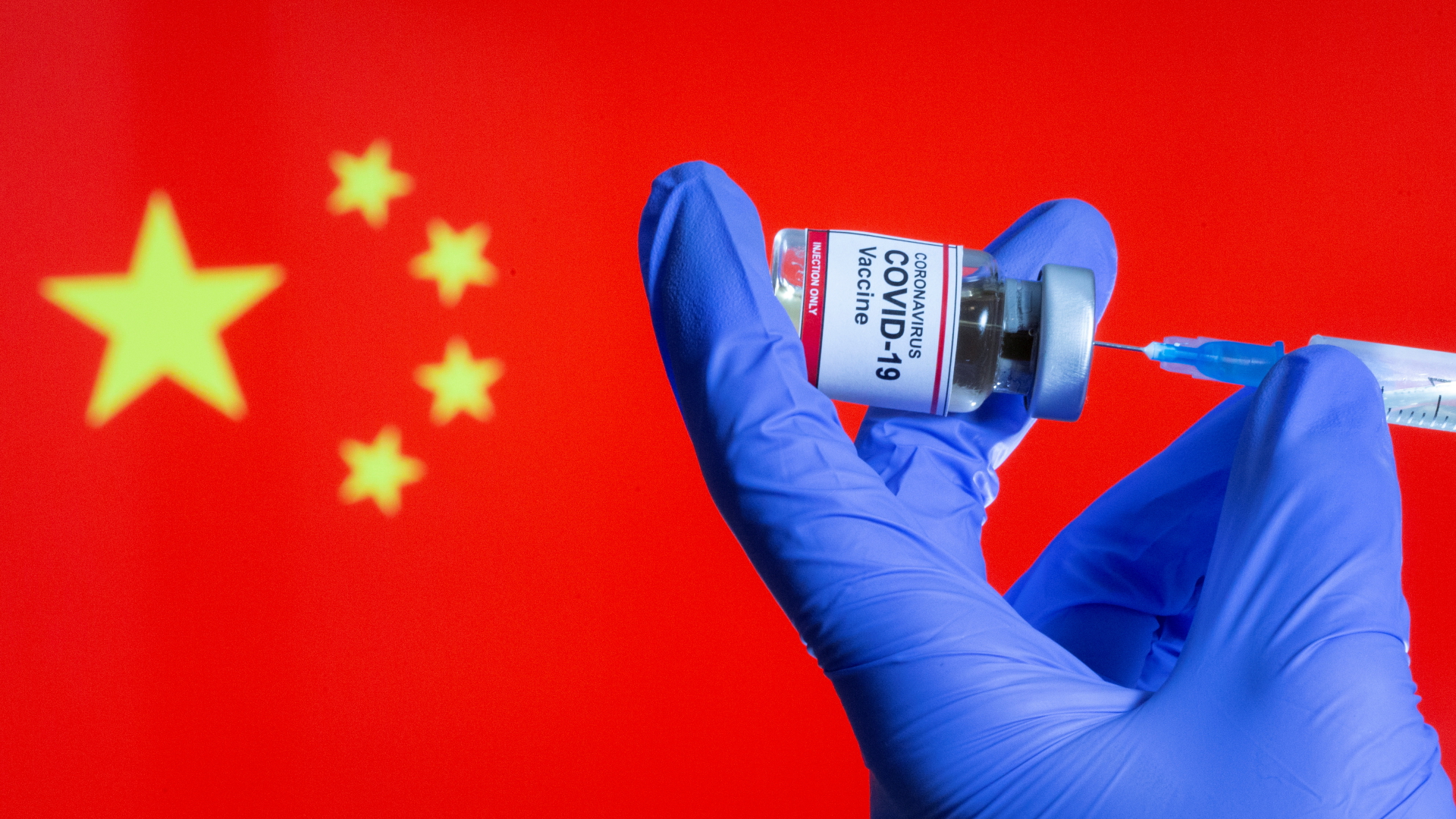 Eine Hand hält eine Ampulle mit einem Corona-Impfstoff vor einer chinesischen Flagge. | REUTERS