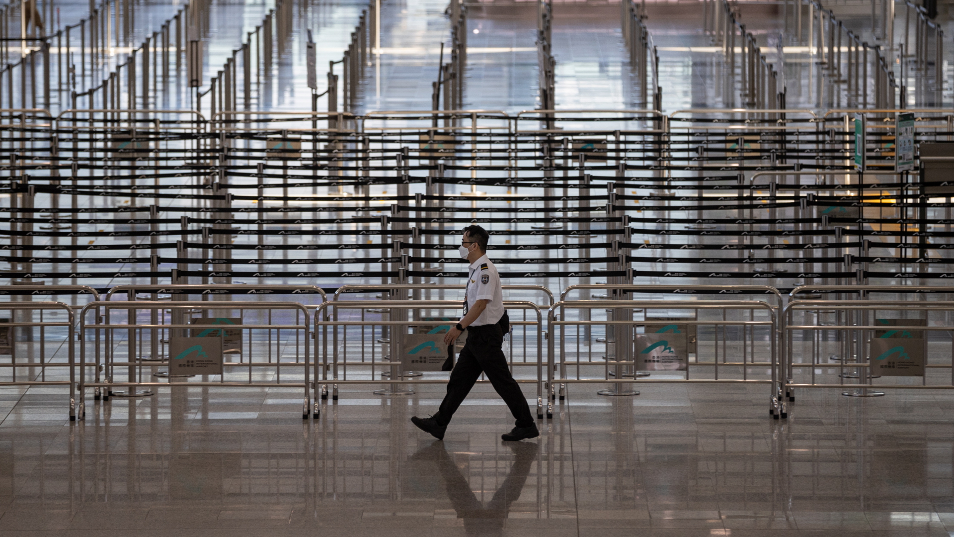 Ein Sicherheitsmitarbeiter läuft am leeren Check-In auf dem Flughafen in Hongkong entlang. | EPA