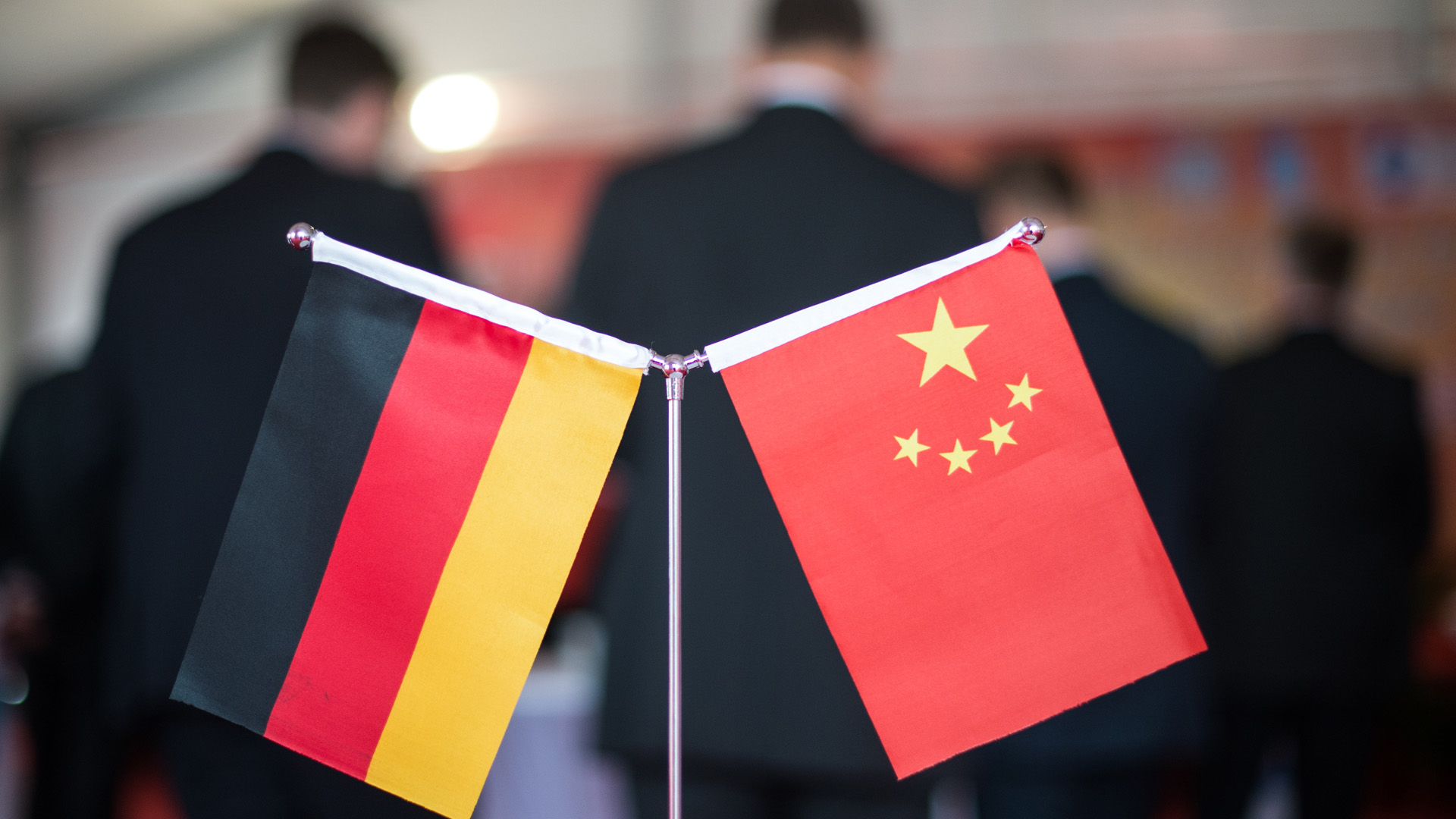 Ein deutsches und ein chinesisches Fähnchen ist vor Männern in dunklen Anzügen zu sehen | picture alliance/dpa
