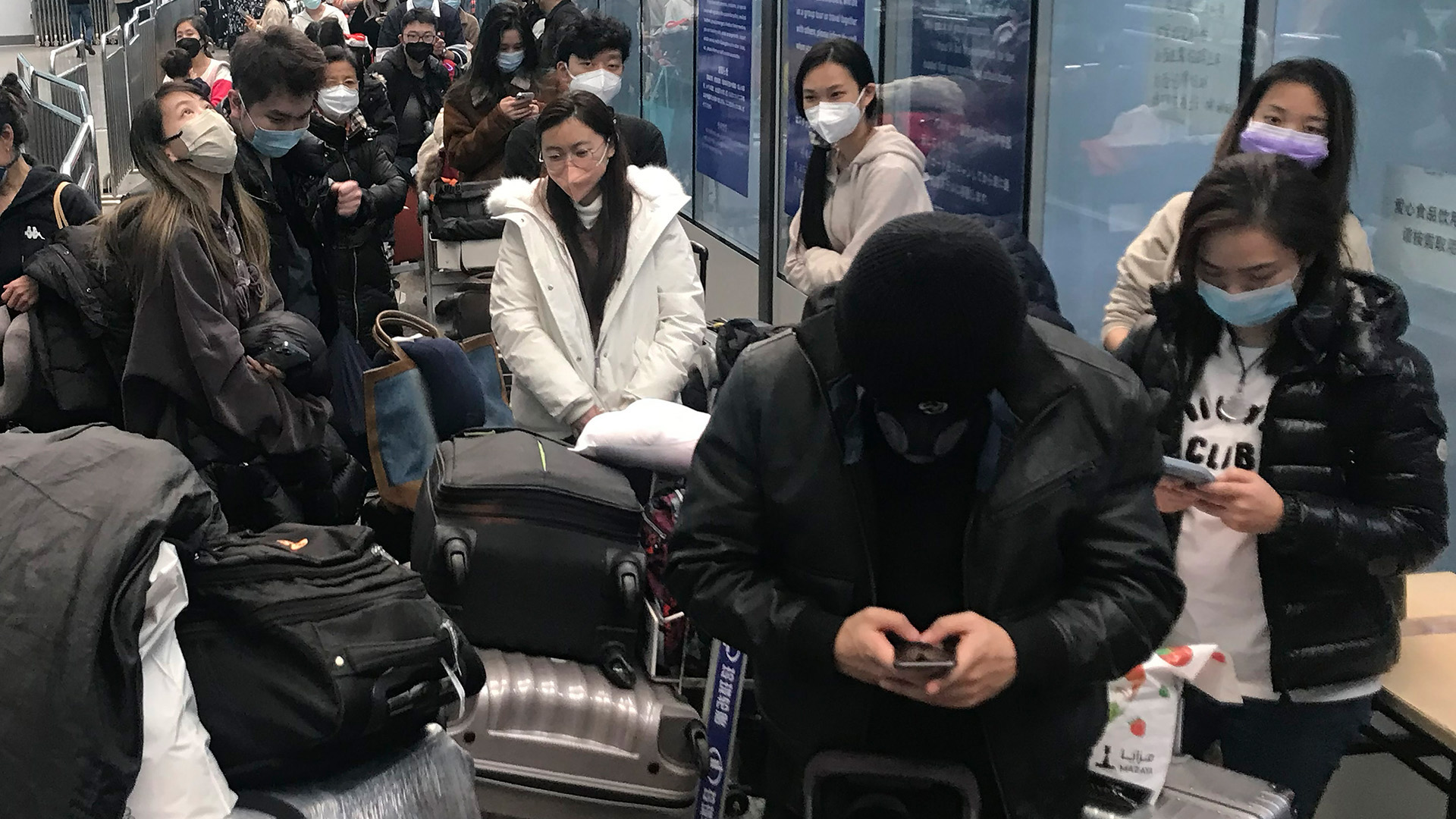 Ankommende Reisende warten auf Busse, um vom Flughafen Guangzhou Baiyun zu Quarantäne-Hotels und -Einrichtungen zu gelangen. | AP