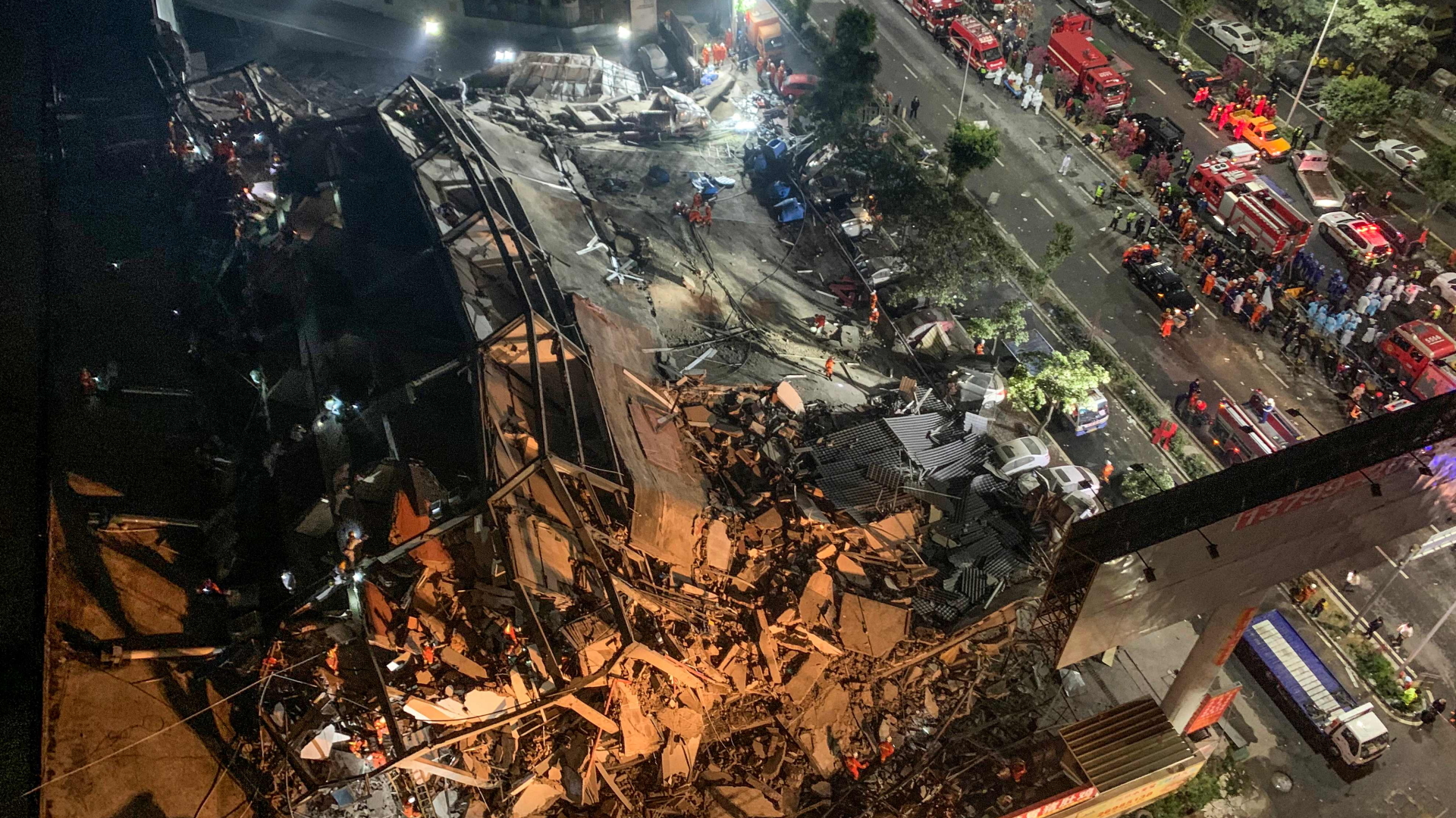 Retter am eingestürzten Hotelgebäude in China | AFP