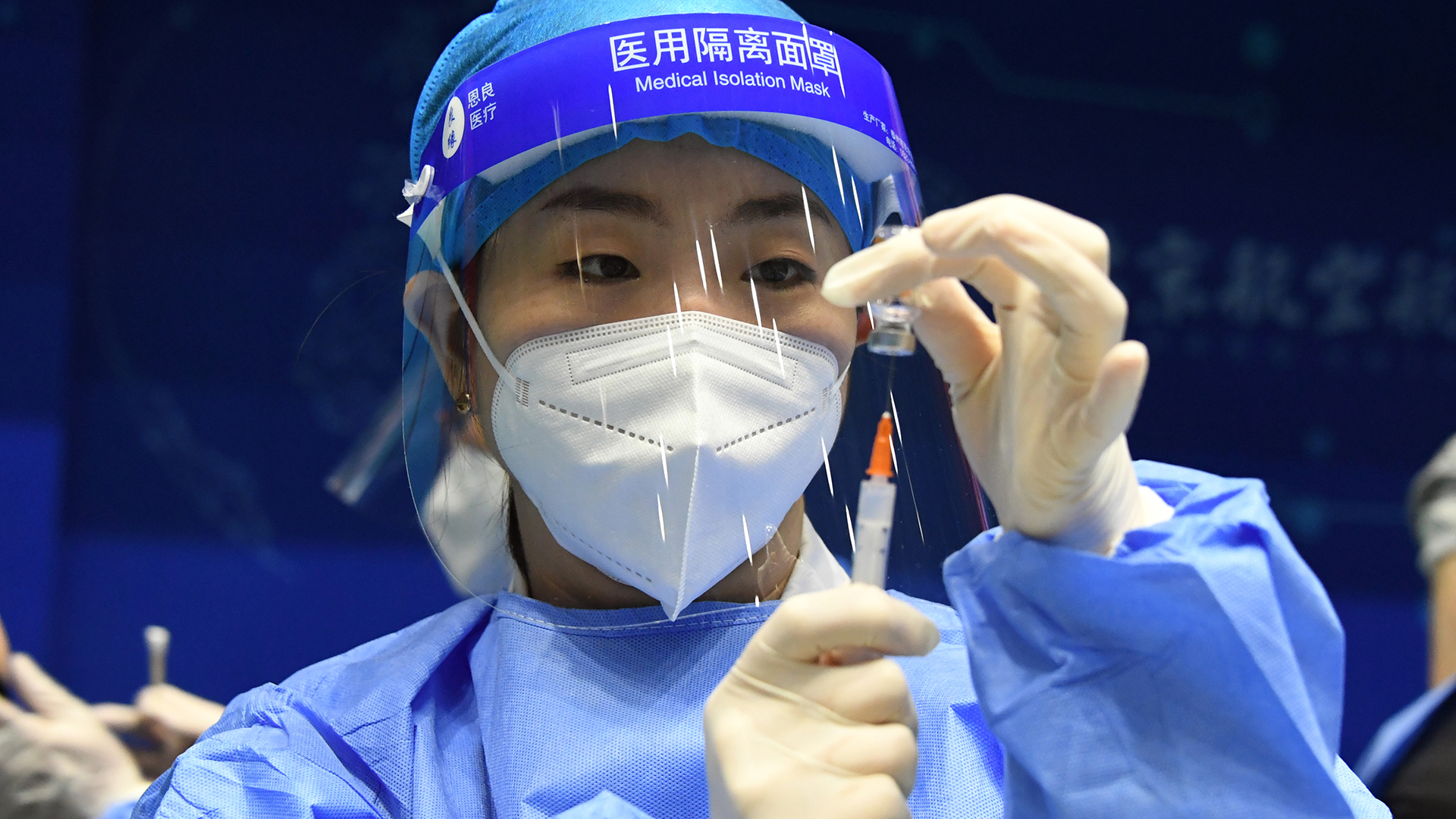 Eine chinesische Mitarbeiterin hält eine Spritze mit Impfstoff in der Hand | dpa