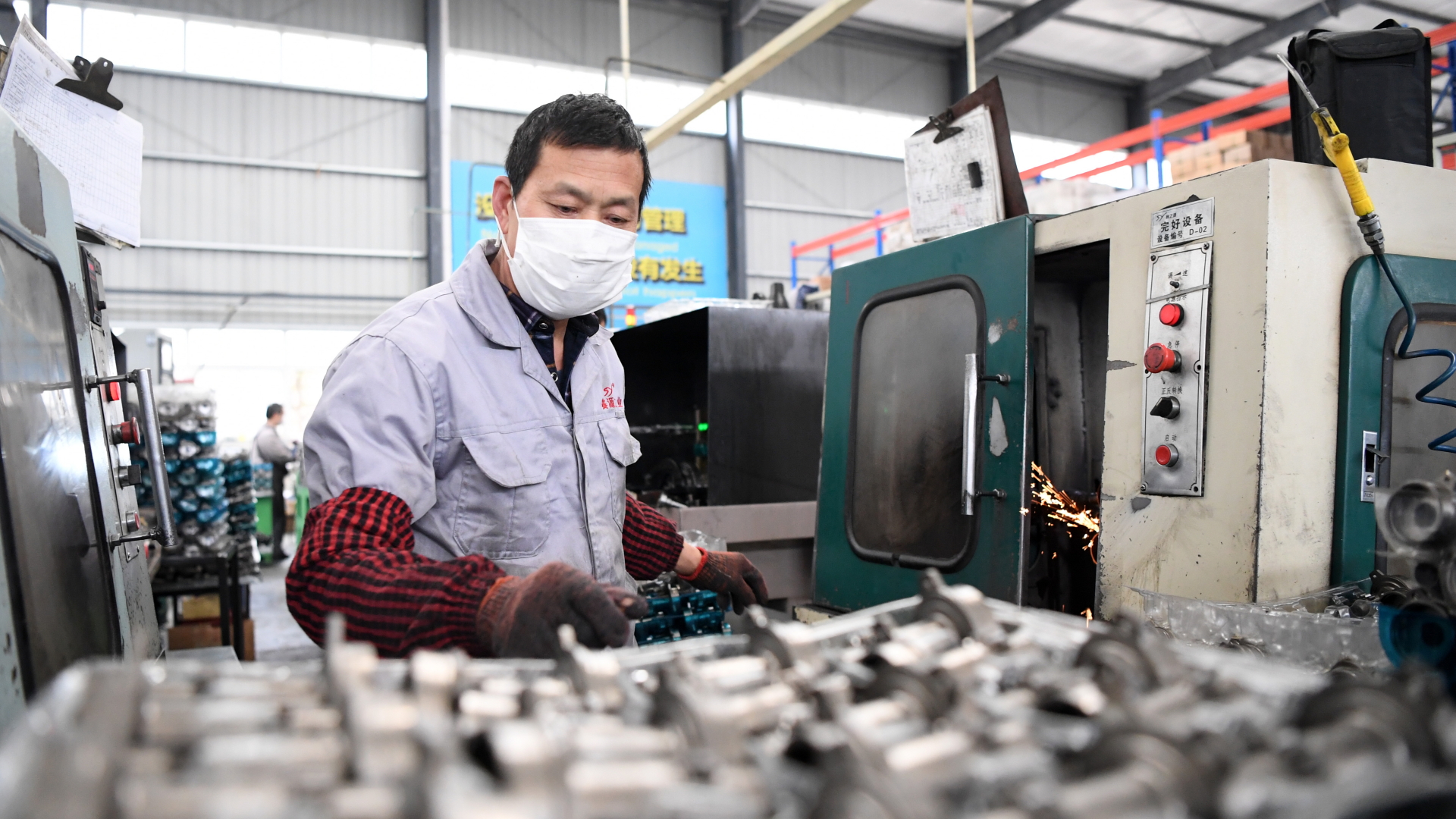 Ein Mann mit Atemschutzmaske arbeitet an einer Produktionslinie für Autozubehör in einer Werkstatt im Bezirk Qijiang.  | dpa