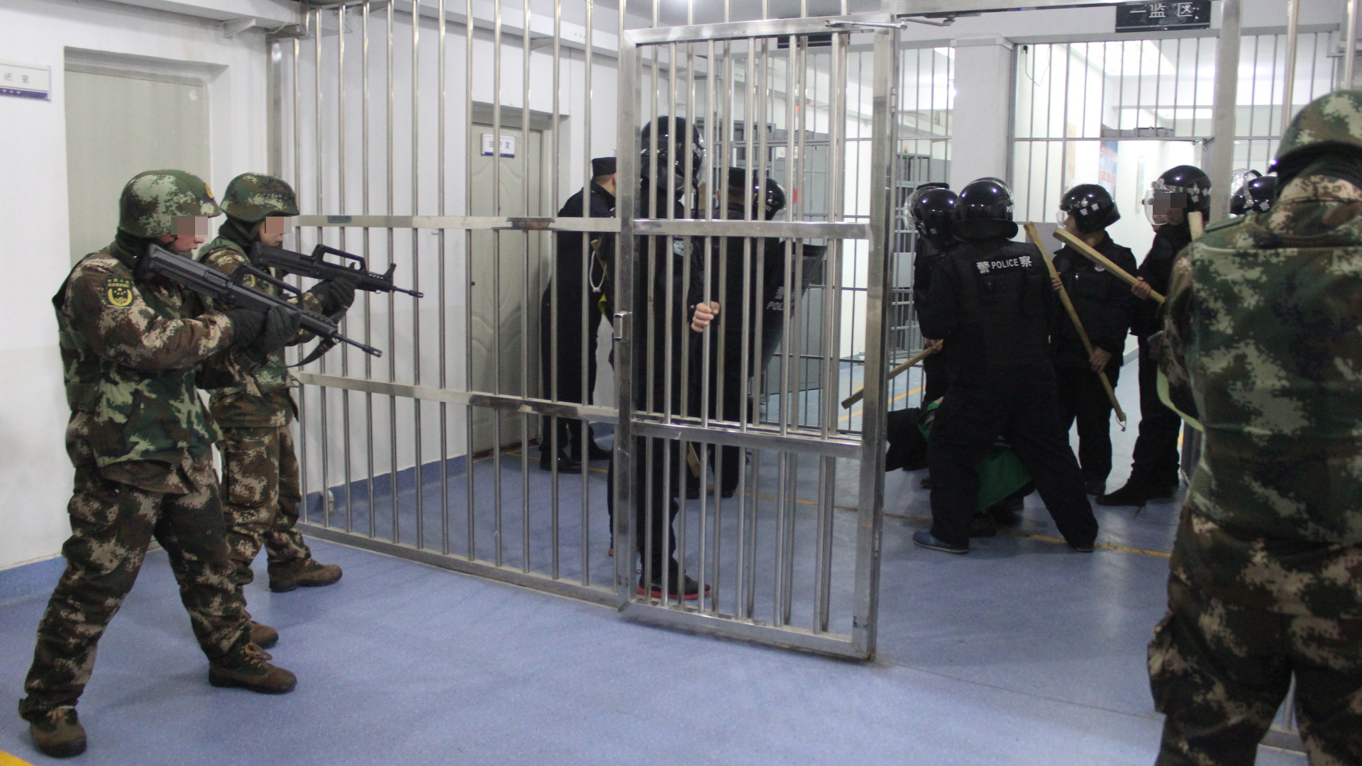 Mit Holzknüppeln bewaffnete Sicherheitskräfte führen einen Inhaftierten in Hand- und Fußfesseln ab. | Xinjiang Police Files