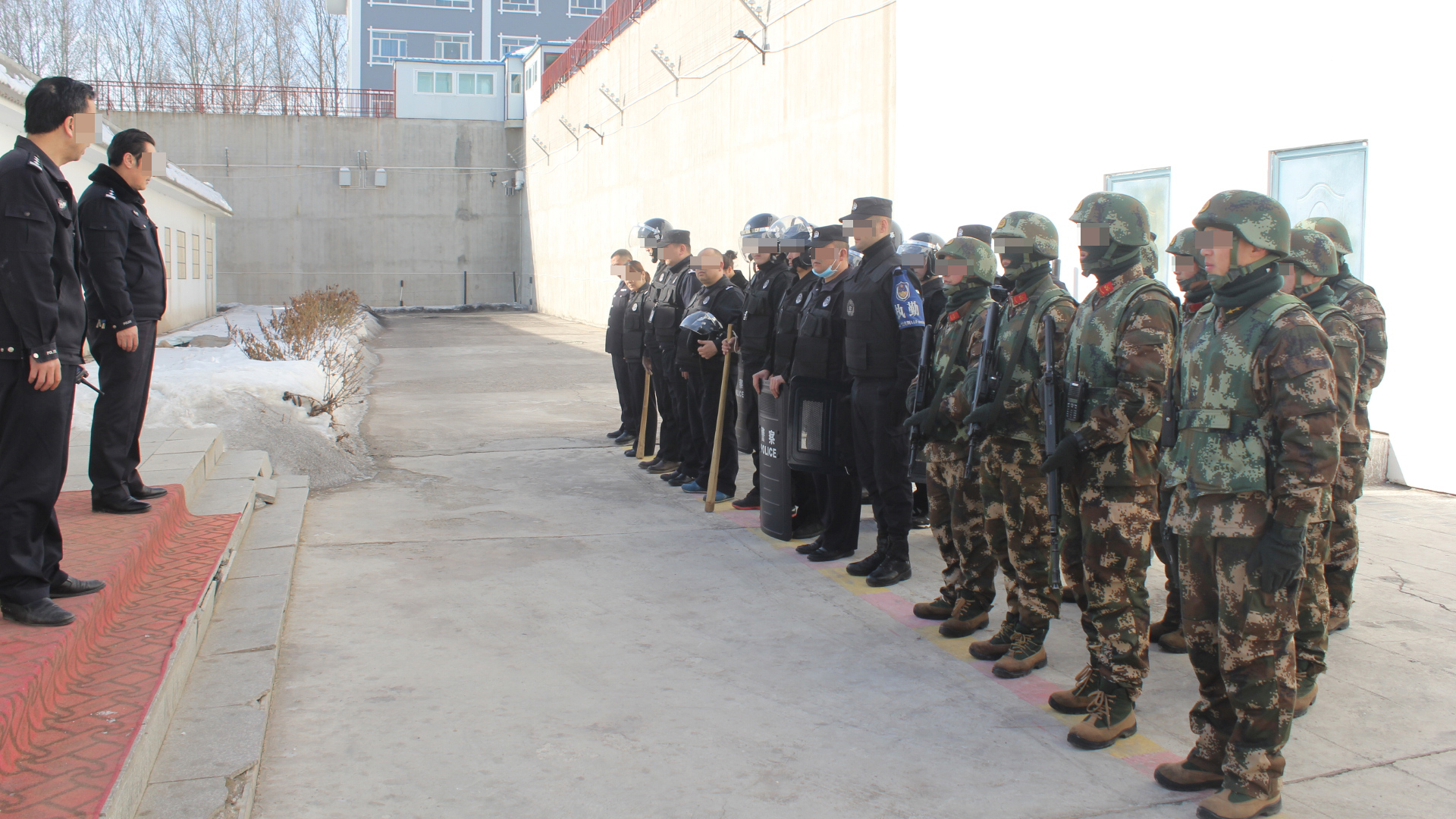 Çin'de bir gözaltı merkezinin önünde ahşap sopalarla donanmış üniformalı insanlar duruyor.  |  Sincan Polis Dosyaları