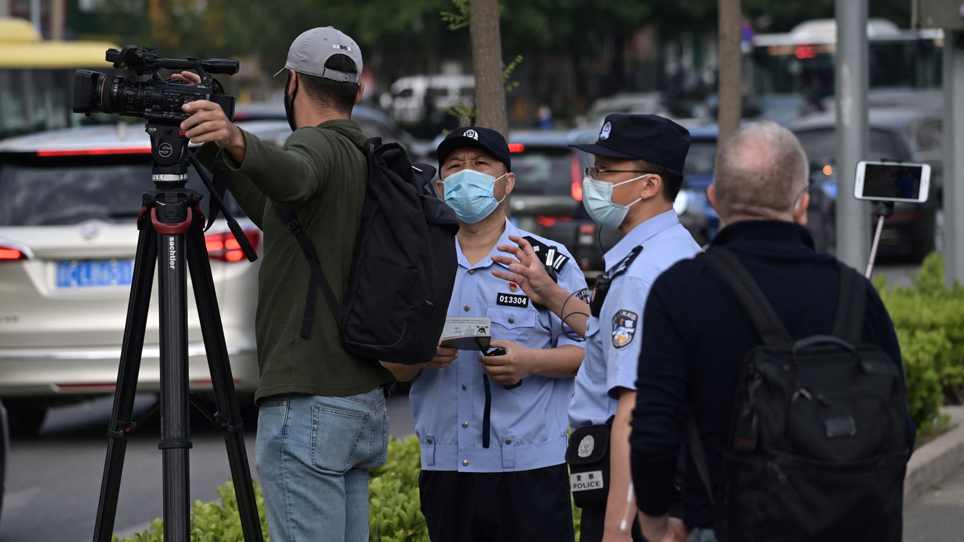 Polizisten befragen eine Journalisten in Peking, als vor einem Spionage-Prozess gegen einen Australier Aufnahmen machen will. | AFP