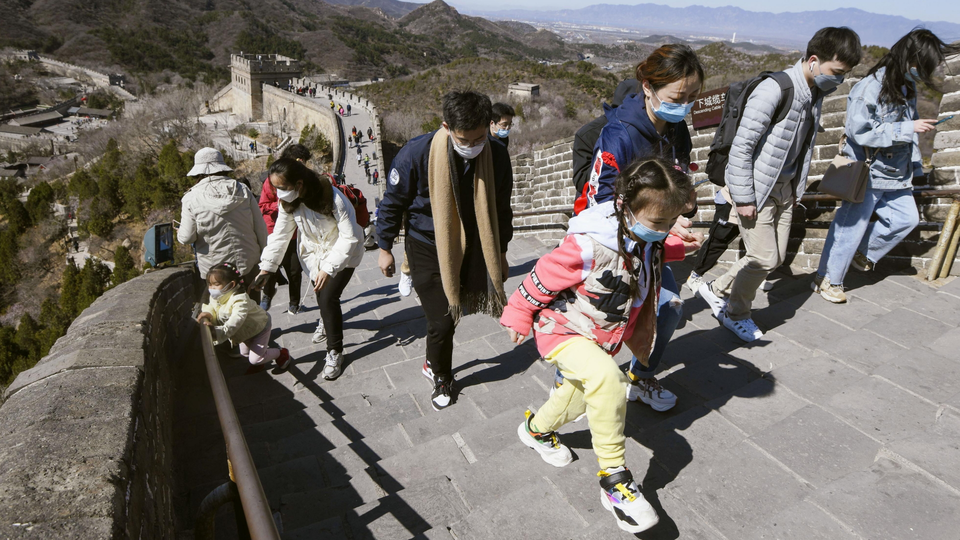 Touristen mit Mundschutz sind auf der Chinesischen Mauer unterwegs.  | dpa