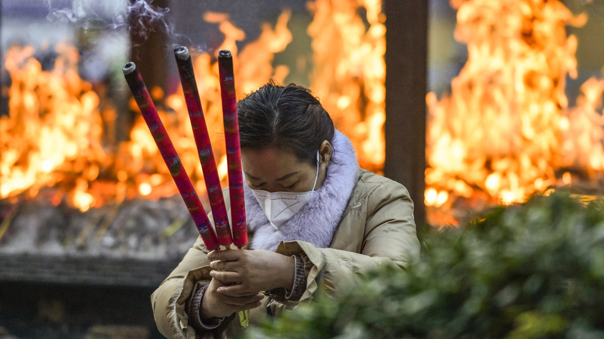 Eine Frau mit Corona-Maske verbrennt Weihrauch und betet um Glück im Zifu-Tempel in Fuyang am ersten Tag des ersten Monats des chinesischen Mondkalenders. | dpa