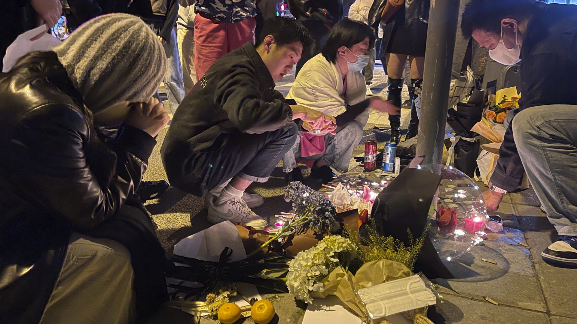 Menschen legen in Shanghai Blumen nieder - zum gedenken an die Opfer des Hochhausbrandes in Urumqi | AP
