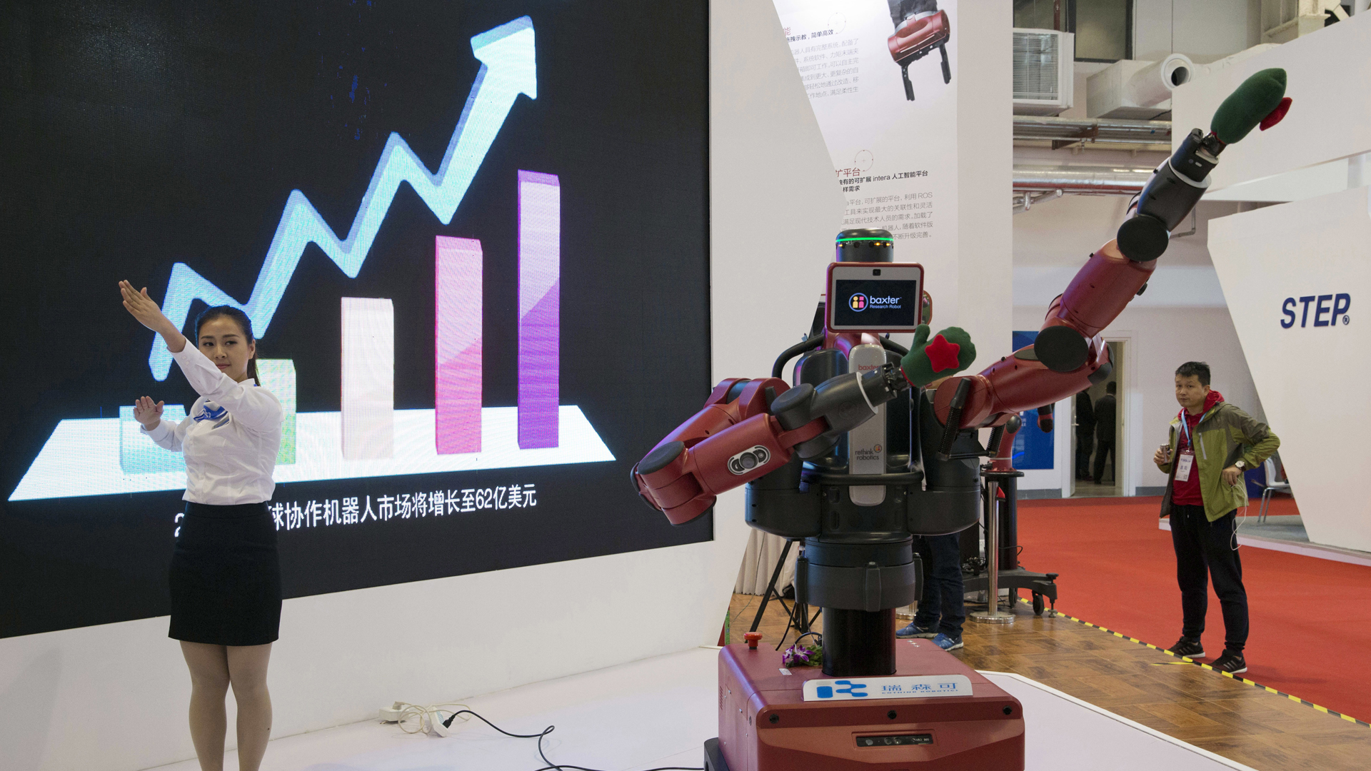 Eine Frau demonstriert die Beweglichkeit eines Roboters der US-Firma Rethink Robotics, die auf dem chinesischen Markt vertreten ist. | picture alliance/AP Photo