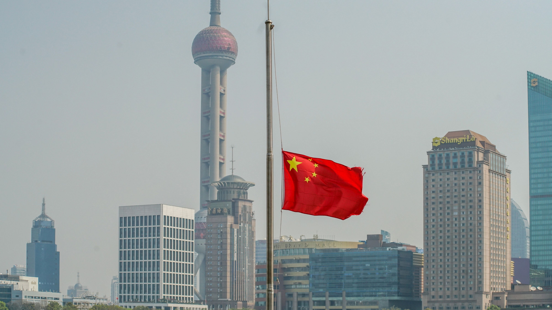 Landesweit sind in China Flaggen auf Halbmast gesetzt, wie hier vor der Silhouette von Shanghai. | AFP