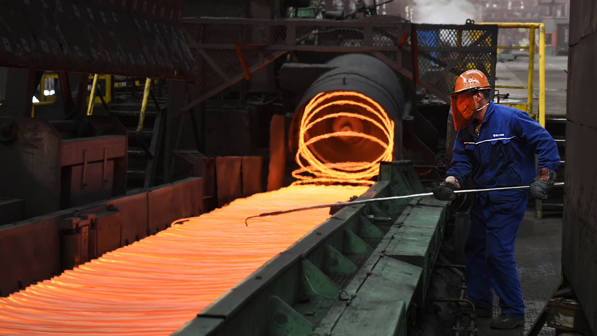 Ein Arbeiter steht an einem Förderband in der Stahlproduktion. | AP