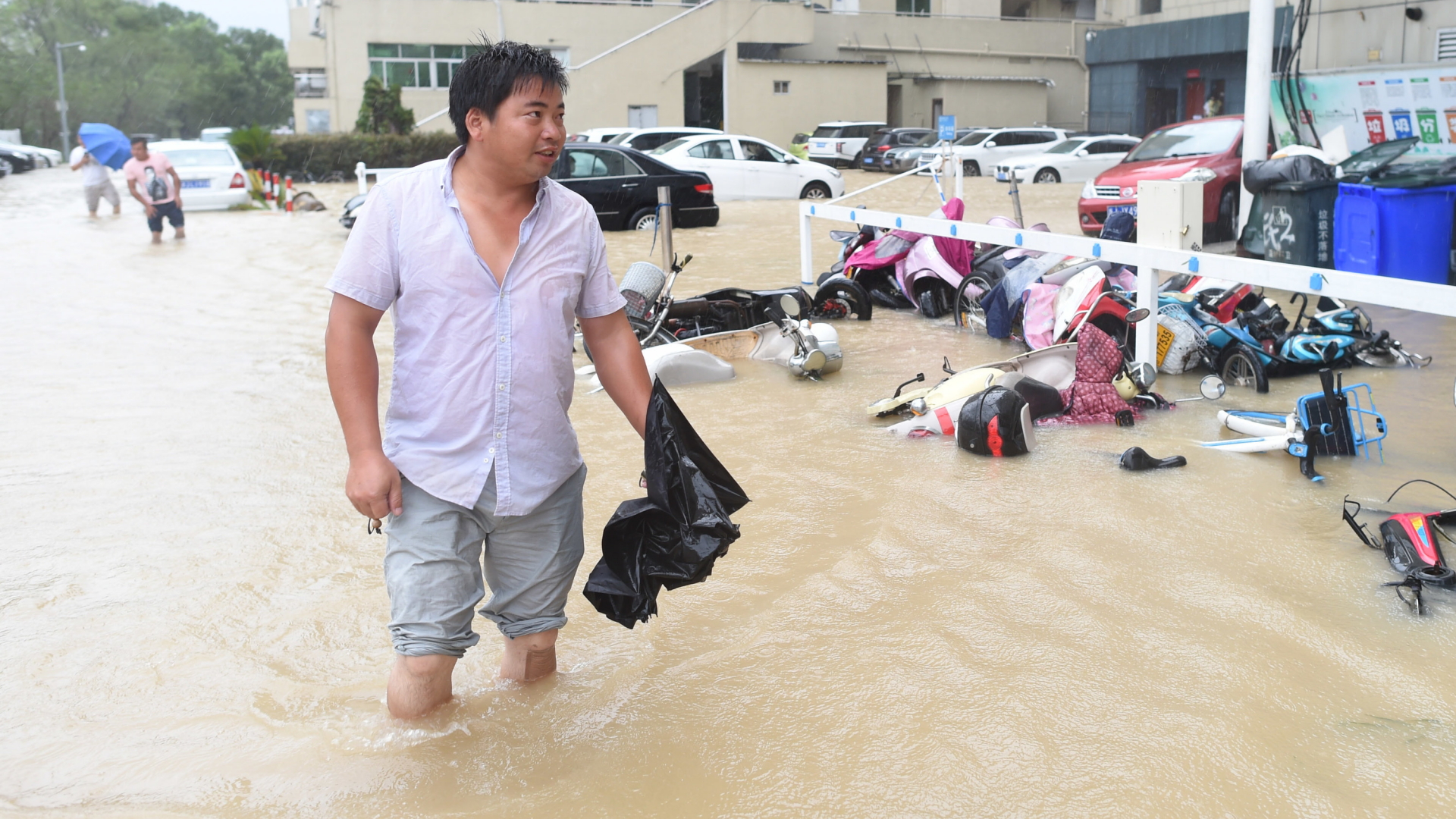 Ein Mann watet durch eine überflutete Straße in der Stadt Wenling, wo Taifun "Lekima" in China auf Land traf. | dpa