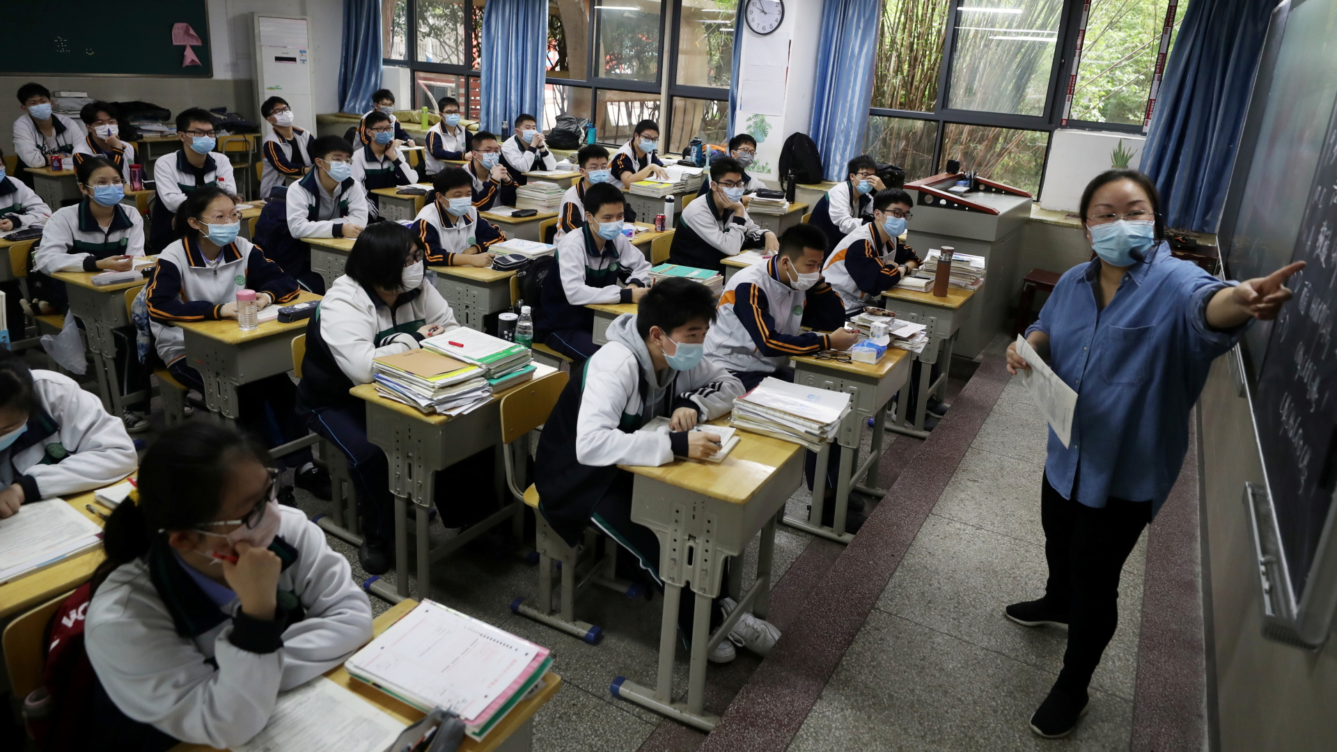 Eine Lehrerin steht vor einer Klasse in einer Oberschule in der chinesischen Metropole Wuhan. Alle tragen Mundschutzmasken. | REUTERS