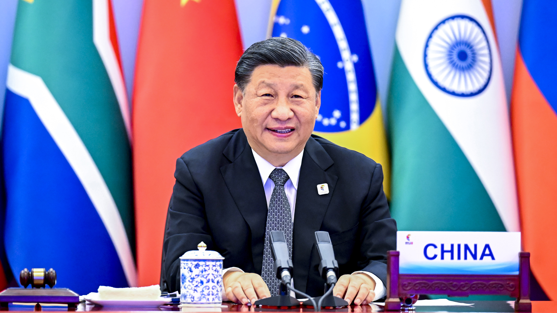 Chinas Staatschef Xi Jinping sitzt vor Mikrophonen an einem Konferenztisch. | picture alliance/dpa/XinHua