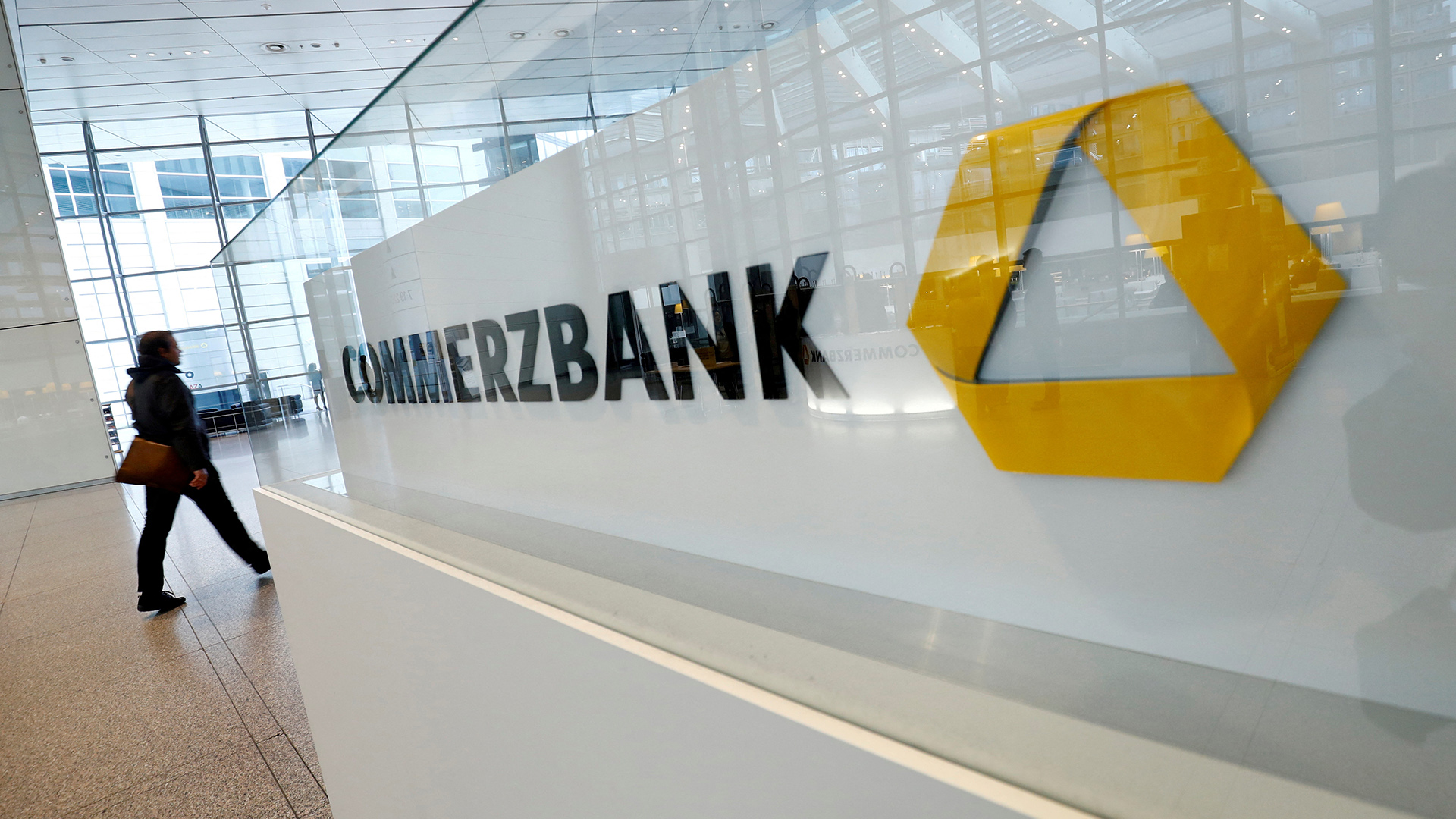 Eine Person läuft am Logo der Commerzbank  in Frankfurt vorbei.