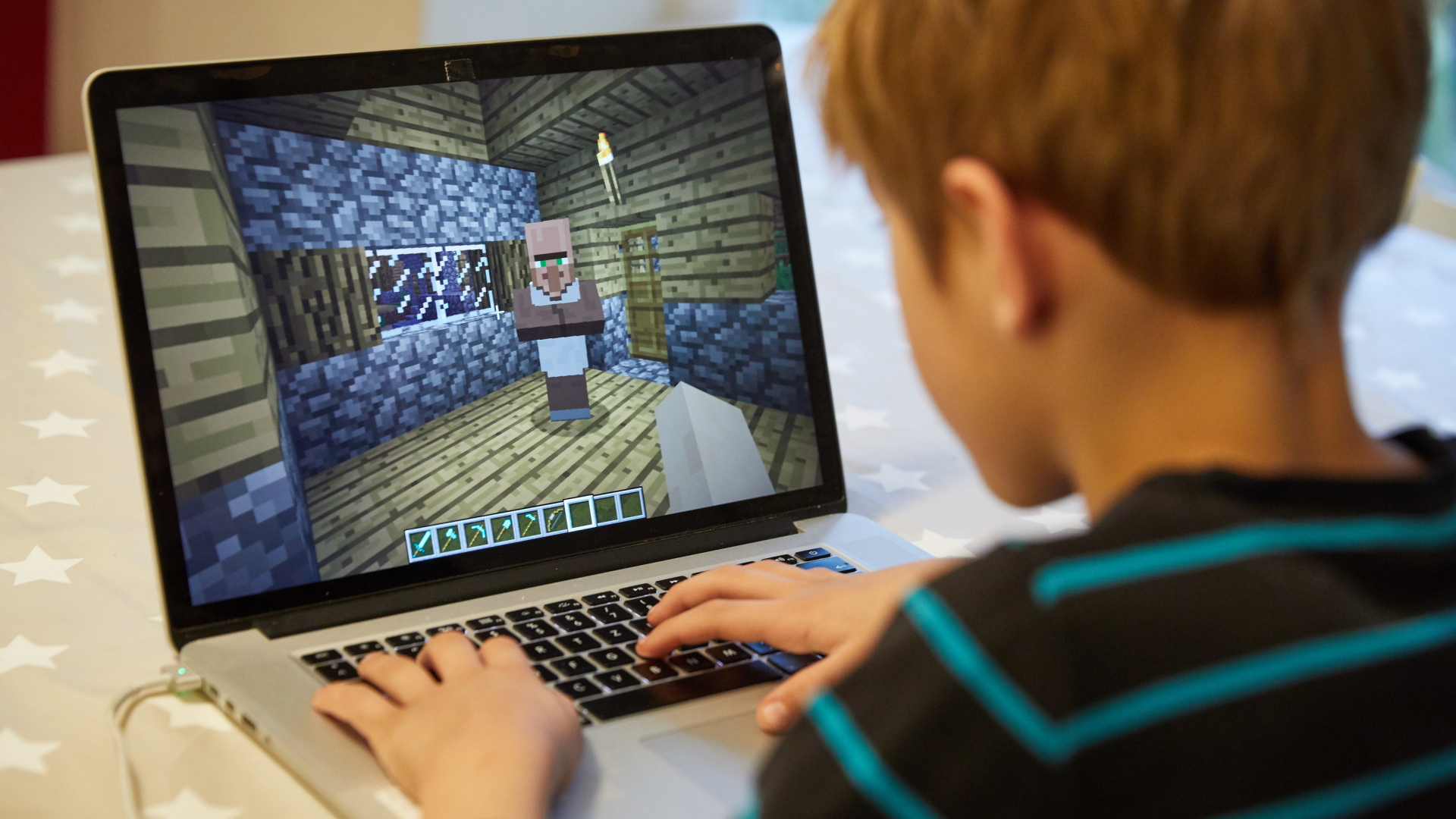 Ein Kind spielt an einem Laptop Minecraft.