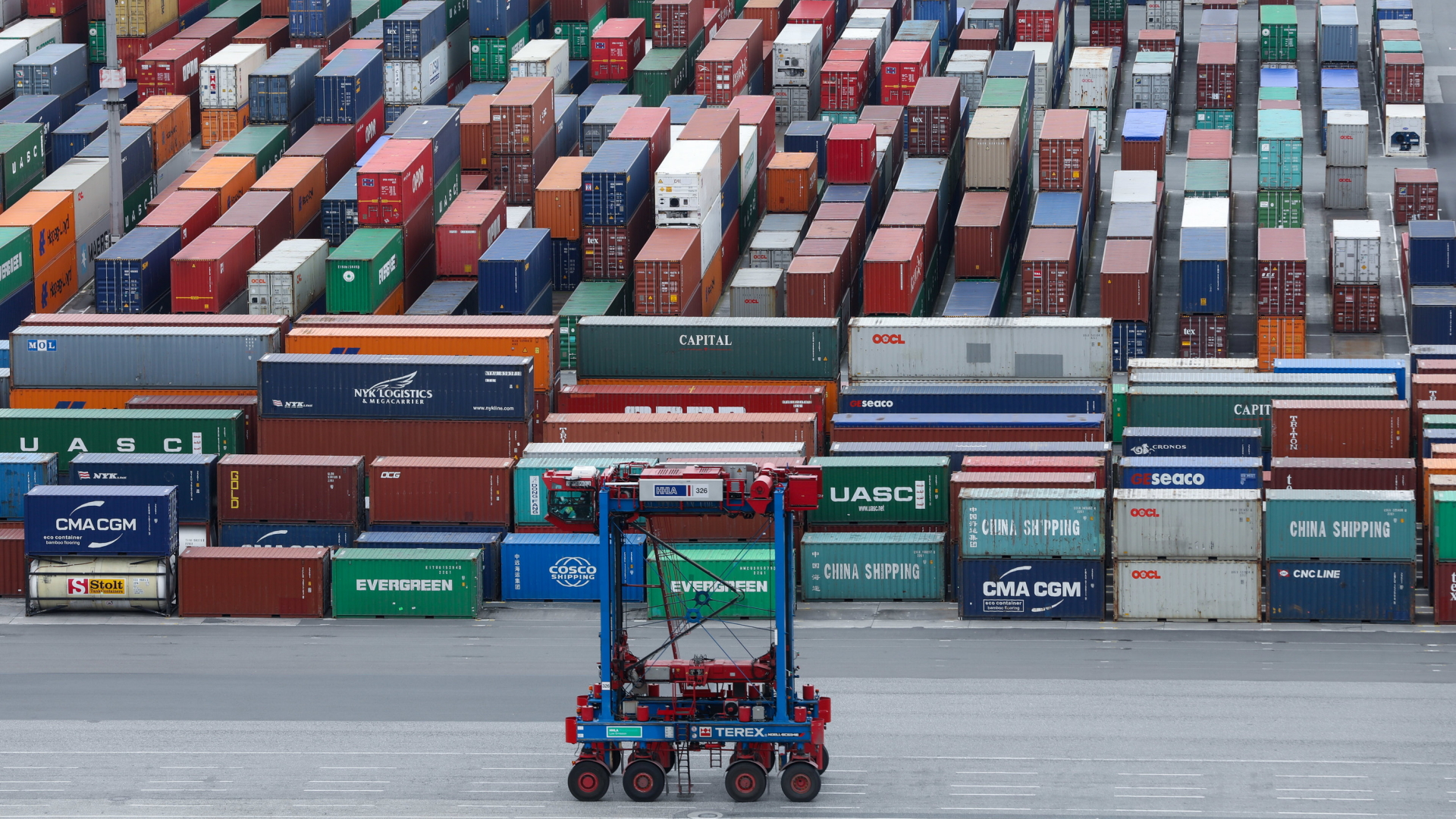 Ein Van-Carrier fährt im Hamburger Hafen an einer Reihe gestapelter Container vorbei. | dpa