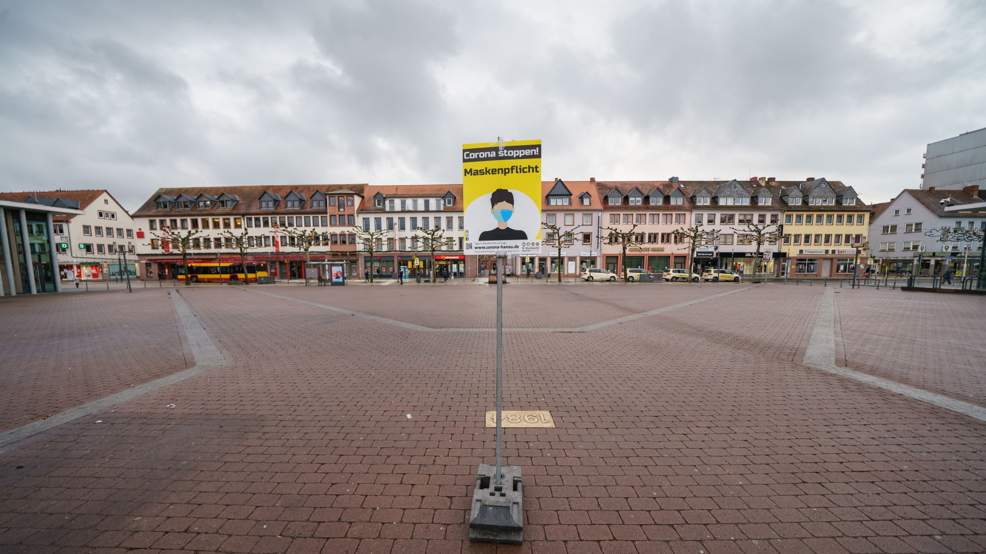 Ein Schild auf dem Marktplatz in Hanau appelliert an die Bürger und erinnert an die Maskenpflicht in diesem Bereich