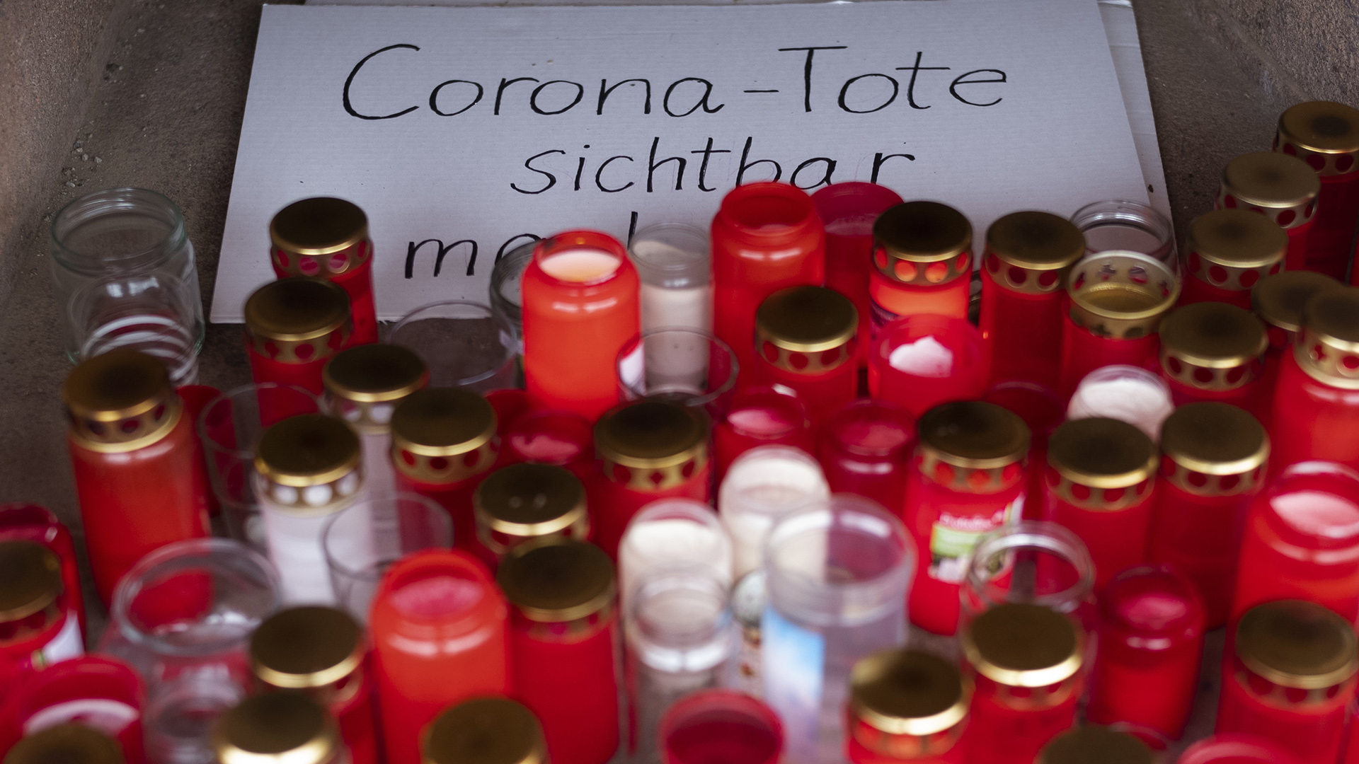  Zahlreiche brennende Grablichter stehen zum Gedenken an Corona-Tote an einem Gedenkort.