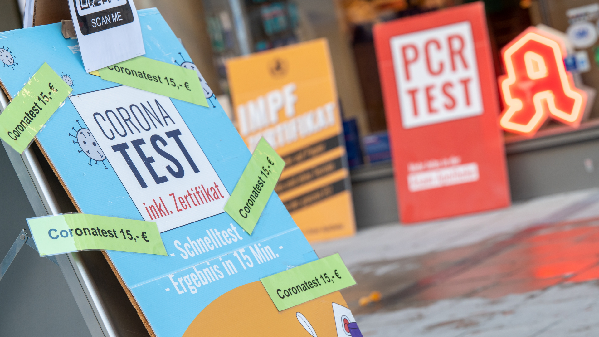 Schilder mit der Aufschrift "Corona Test" stehen vor einer Apotheke in der Innenstadt.  | dpa