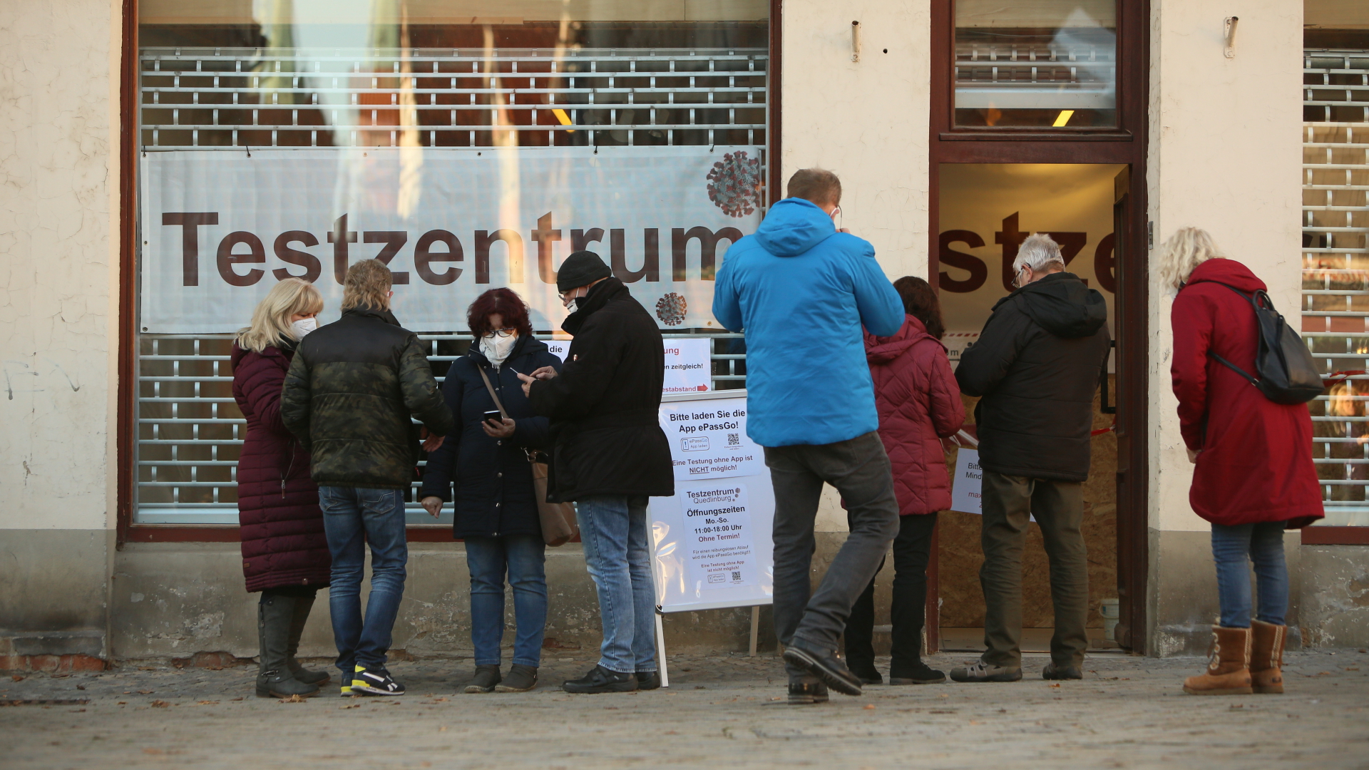 Menschen stehen vor einem Testzentrum in der Adventsstadt Quedlinburg.  | dpa
